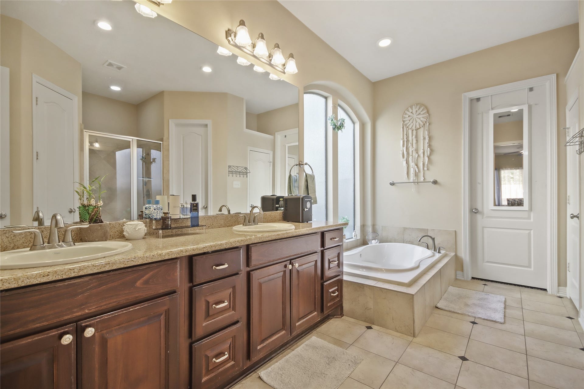 A luxury spa like primary bathroom with dual vanities with granite counters, soaking jet tub, and a separate shower.