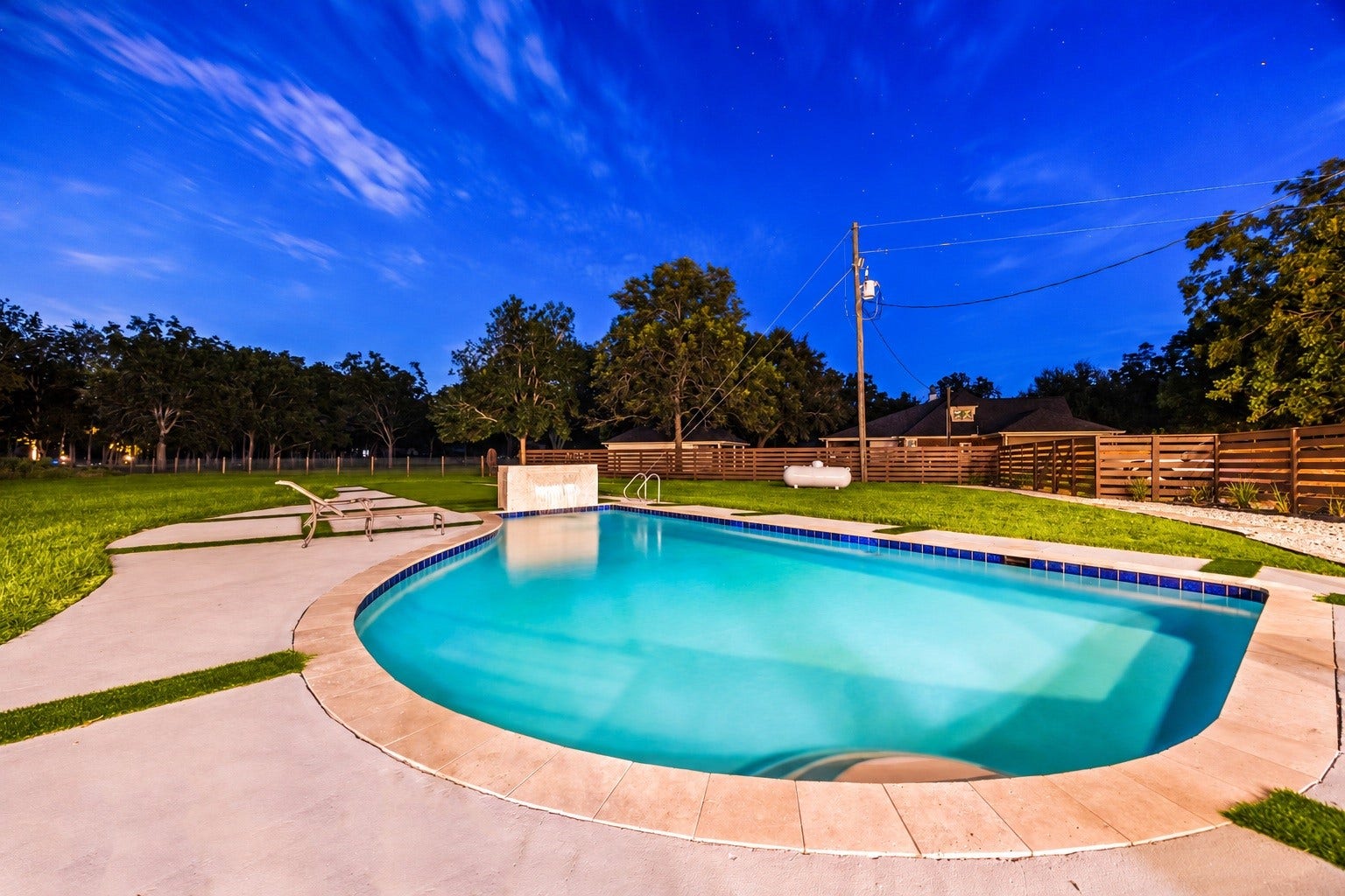 6830 Bois D Arc Lane, Fulshear, TX 77406 As evening falls, the pool's water feature and lighting create a serene backyard retreat.