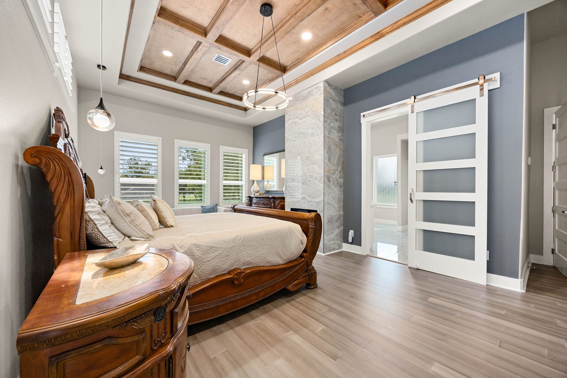 6830 Bois D Arc Lane, Fulshear, TX 77406 The primary bedroom is a true retreat, with a coffered wood ceiling, designer pendant lighting, and its own private fireplace setting a warm, elegant tone.
