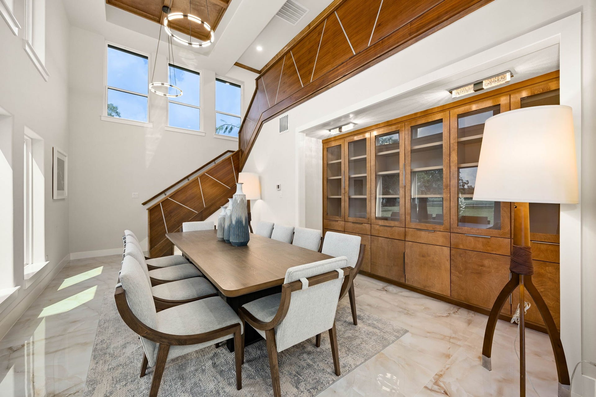 6830 Bois D Arc Lane, Fulshear, TX 77406 Custom wood built-ins and a statement dining table offer even more room to gather, tucked beneath the home's dramatic staircase.