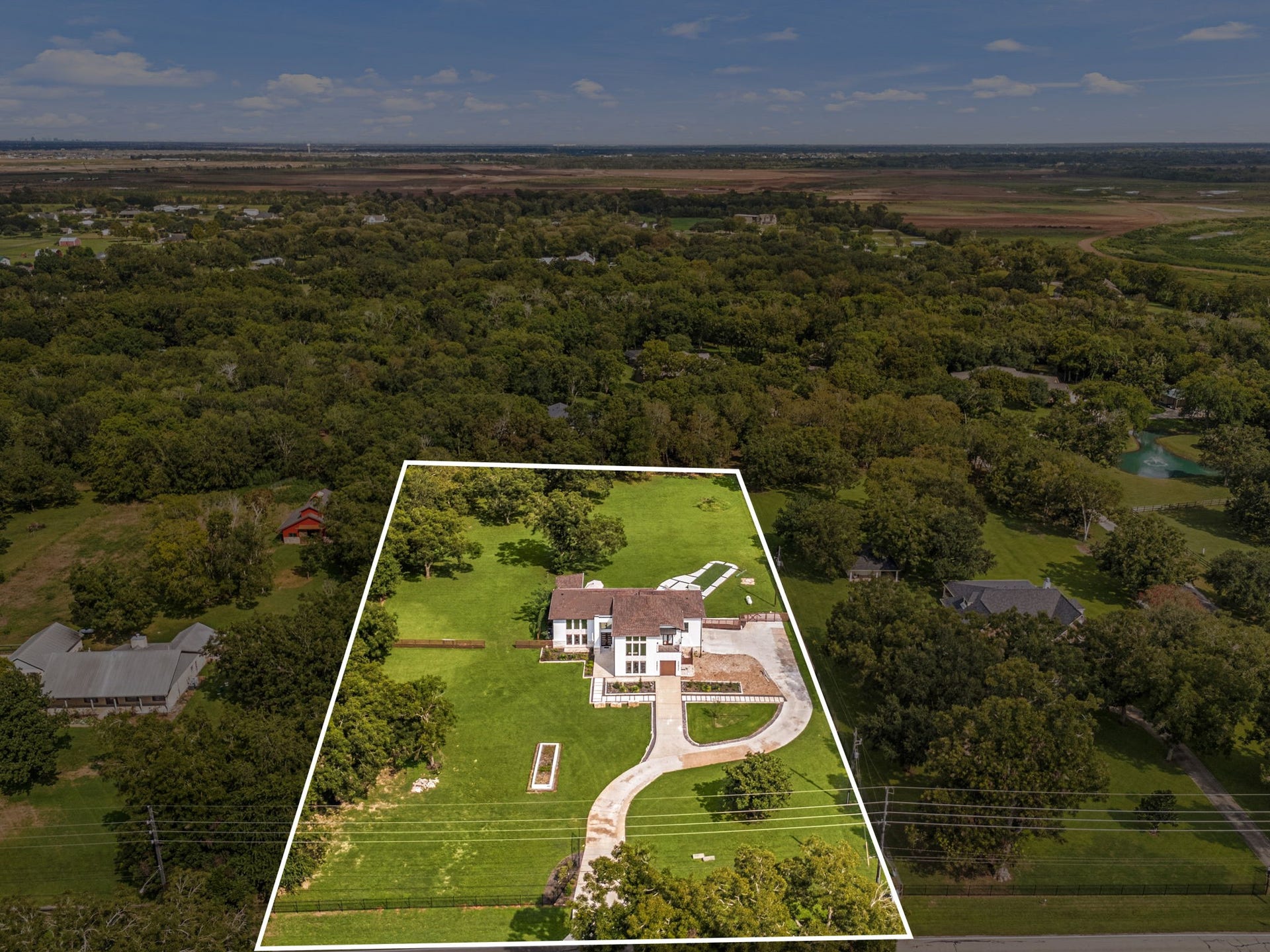 6830 Bois D Arc Lane, Fulshear, TX 77406 This aerial view highlights the property's large, tree-studded lot, with the boundary outlined to show the full scope of the grounds surrounding the home.