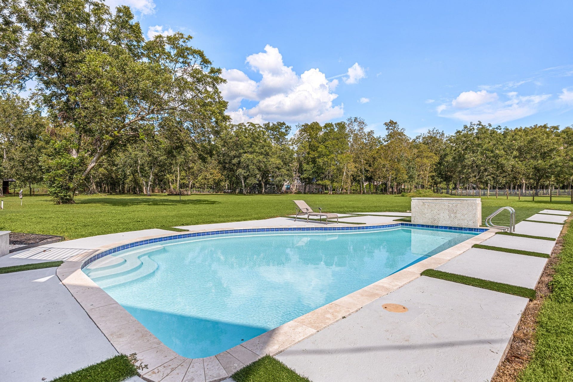 6830 Bois D Arc Lane, Fulshear, TX 77406 The resort-style pool features a tanning ledge, a stone water feature, and a spacious travertine-look deck for lounging.