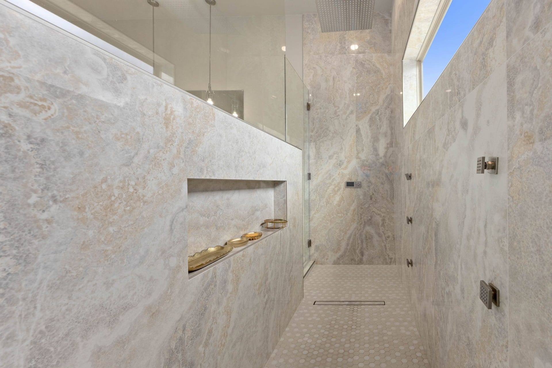 6830 Bois D Arc Lane, Fulshear, TX 77406 This spa-inspired shower pairs floor-to-ceiling tile and frameless glass with a rainfall showerhead, multiple body sprays, a linear drain, and a recessed niche. The digital panel on the far wall provides precise control of the water temperature and pressure for a personalized shower experience.