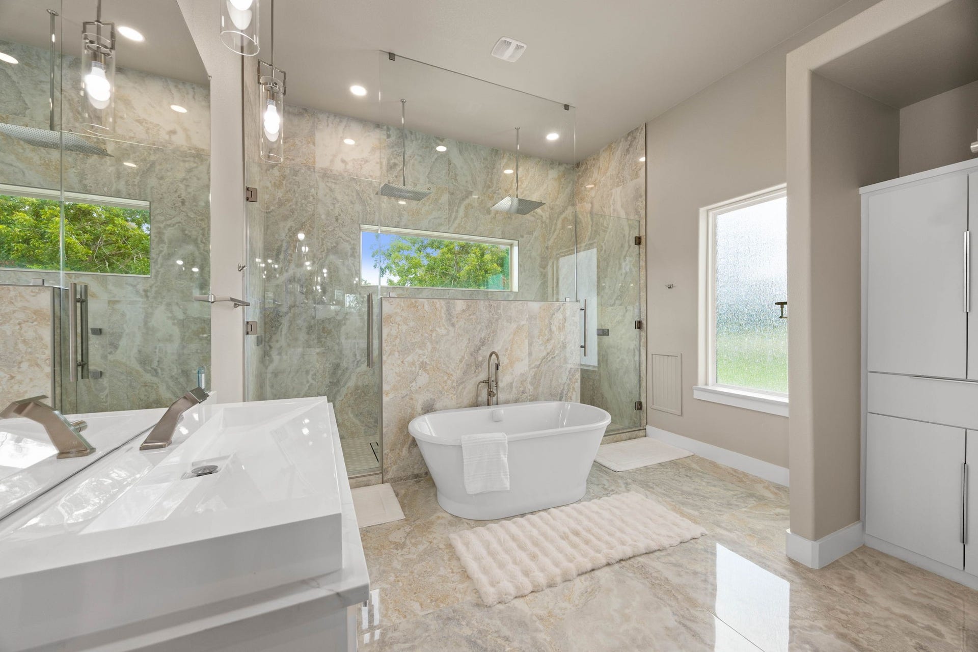 6830 Bois D Arc Lane, Fulshear, TX 77406 Soaring ceilings, expansive mirrors, contemporary pendant lighting, and thoughtfully placed windows enhance the bathrooms impressive scale while filling the space with natural light.