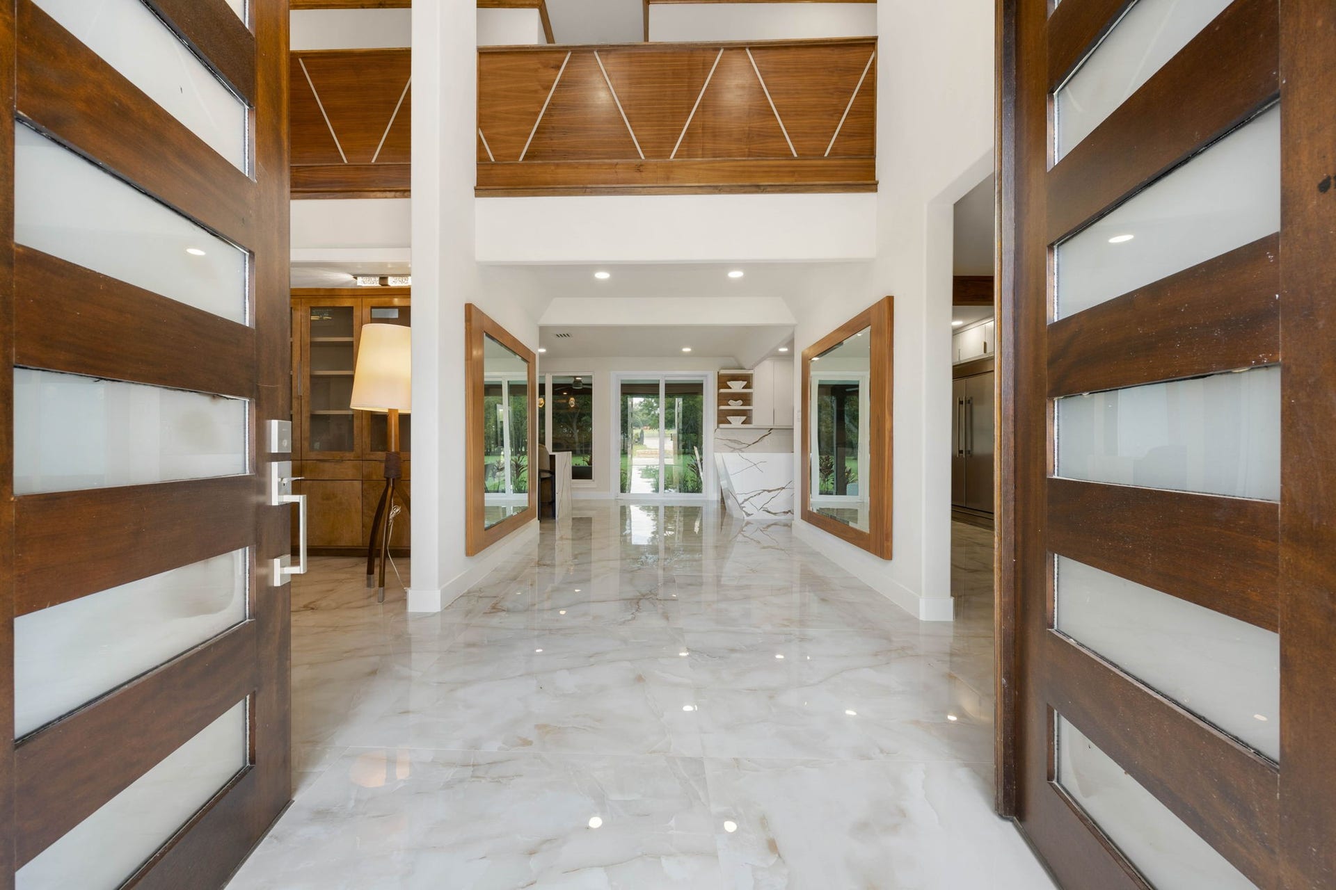 6830 Bois D Arc Lane, Fulshear, TX 77406 Double wood doors open to a dramatic marble foyer, where mirrored wood-framed accents and natural light set an elegant tone from the moment you step inside.