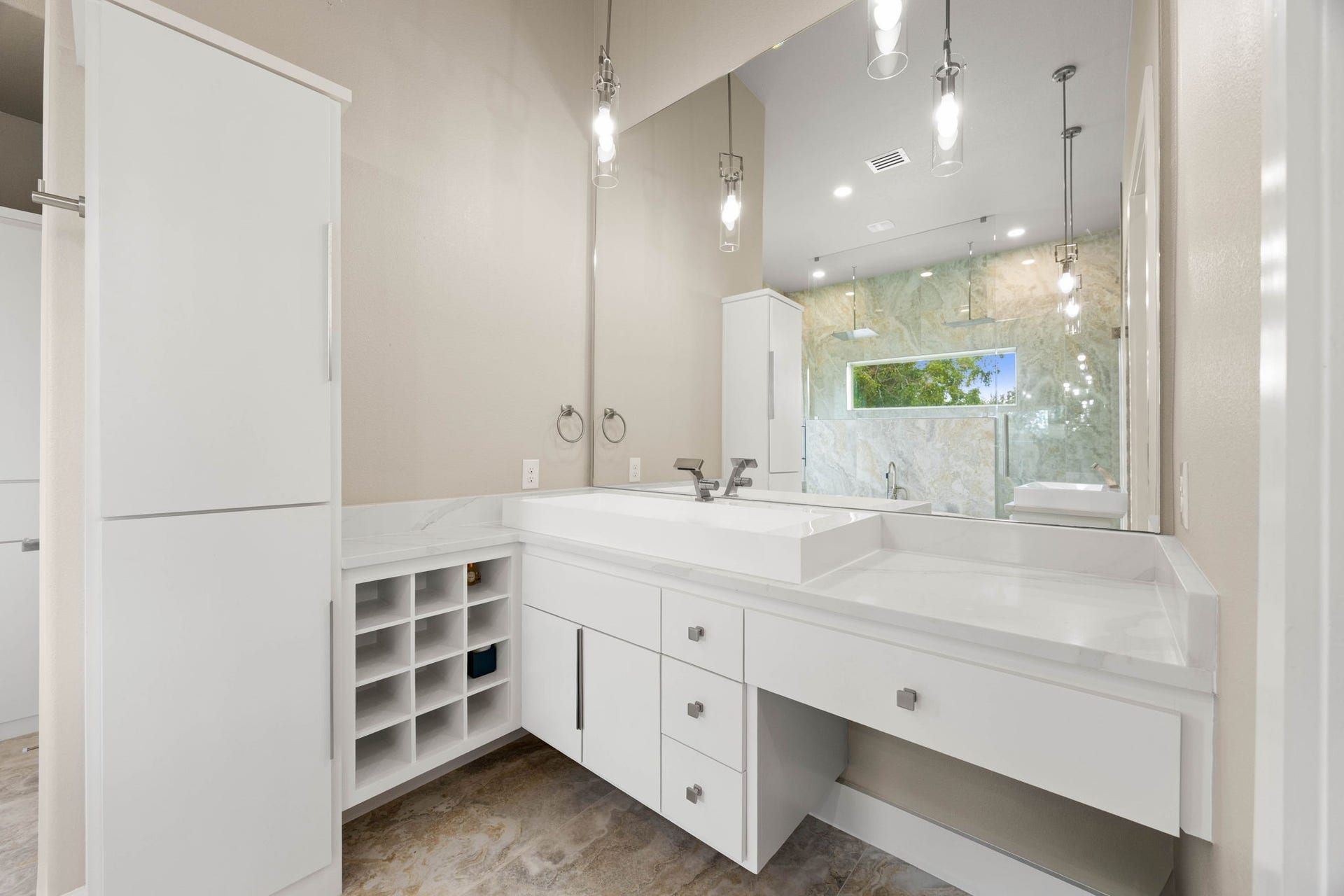 6830 Bois D Arc Lane, Fulshear, TX 77406 The secondary sink area features a sleek integrated basin, an oversized mirror, pendant lighting, abundant cabinetry, and built-in cubbies for organized storage.