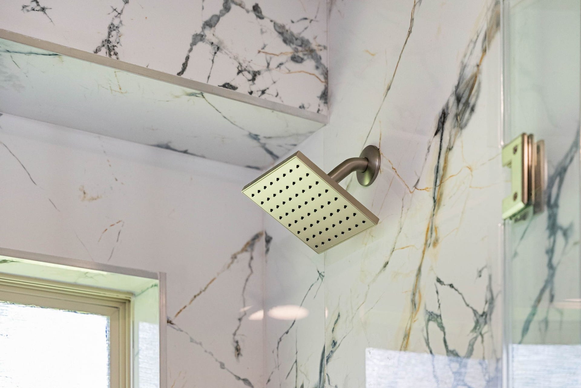 6830 Bois D Arc Lane, Fulshear, TX 77406 A closer look showcases the oversized rainfall showerhead, surrounded by dramatic veined tile and integrated accent lighting for a polished, spa-like finish.