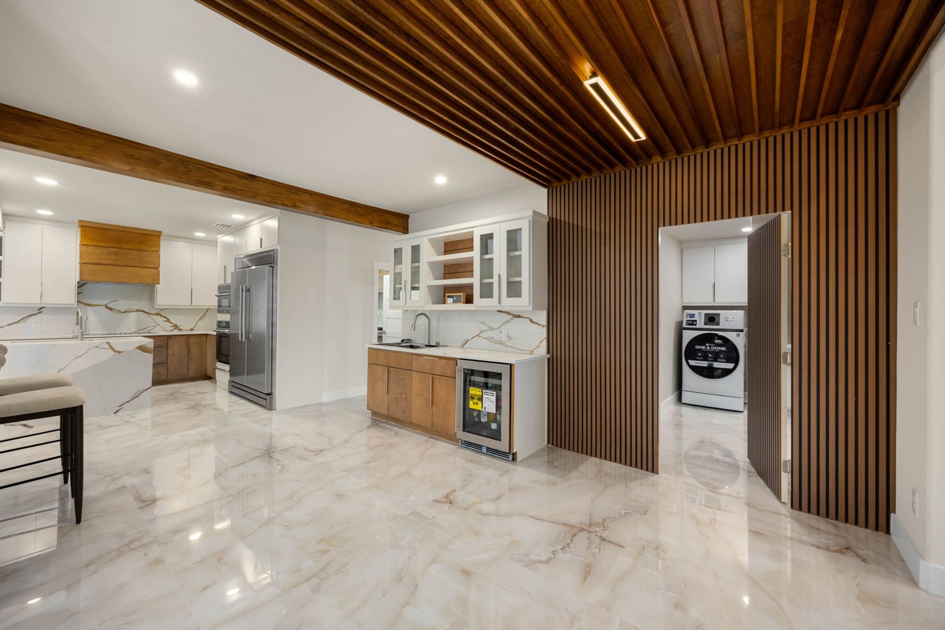 6830 Bois D Arc Lane, Fulshear, TX 77406 Tucked behind a sleek wood-slat door off the kitchen, the laundry room stays out of sight until needed a thoughtful, custom touch.