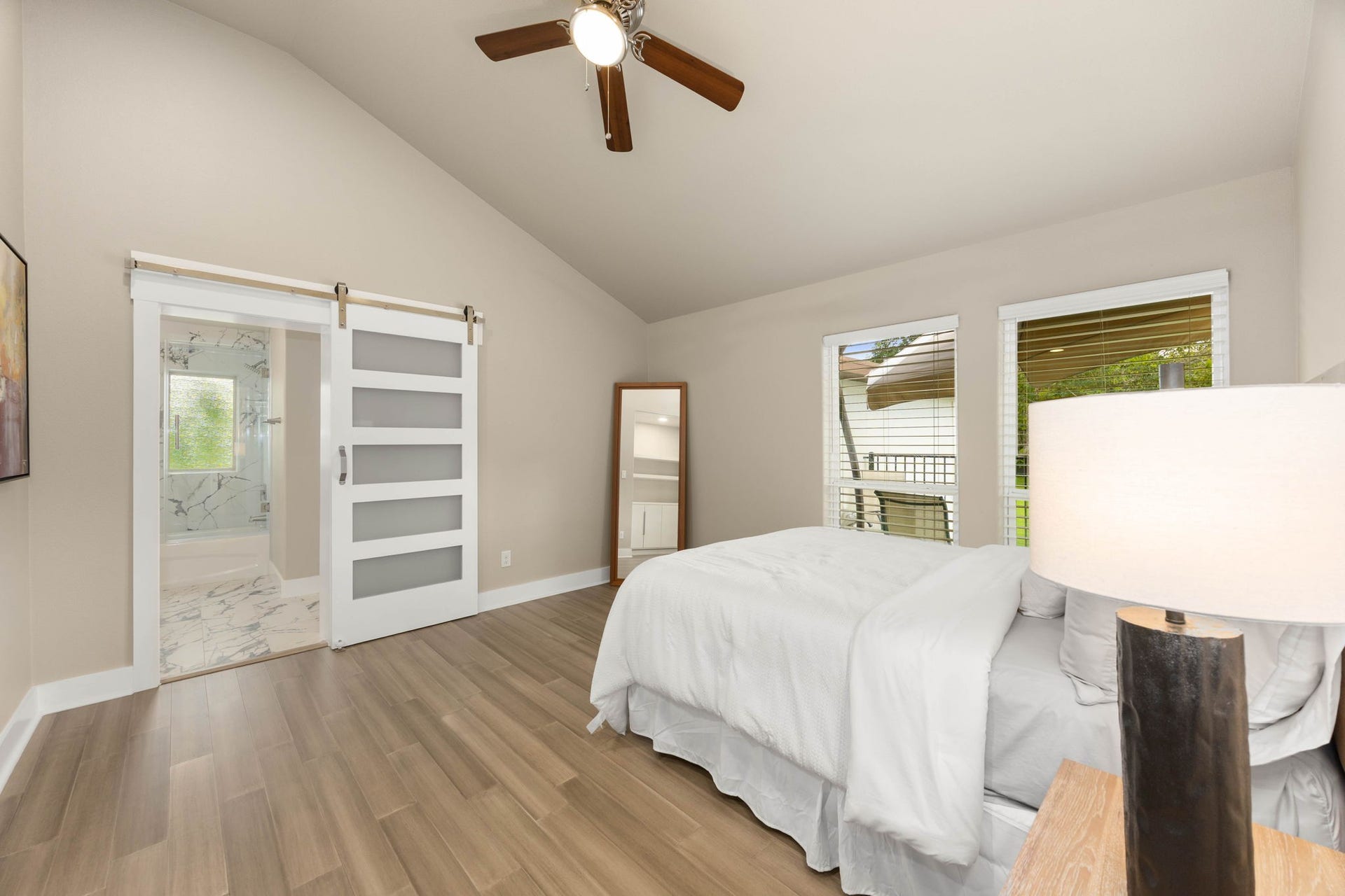 6830 Bois D Arc Lane, Fulshear, TX 77406 A secondary bedroom offers a ceiling fan, a full-length mirror, and warm wood-tone flooring.