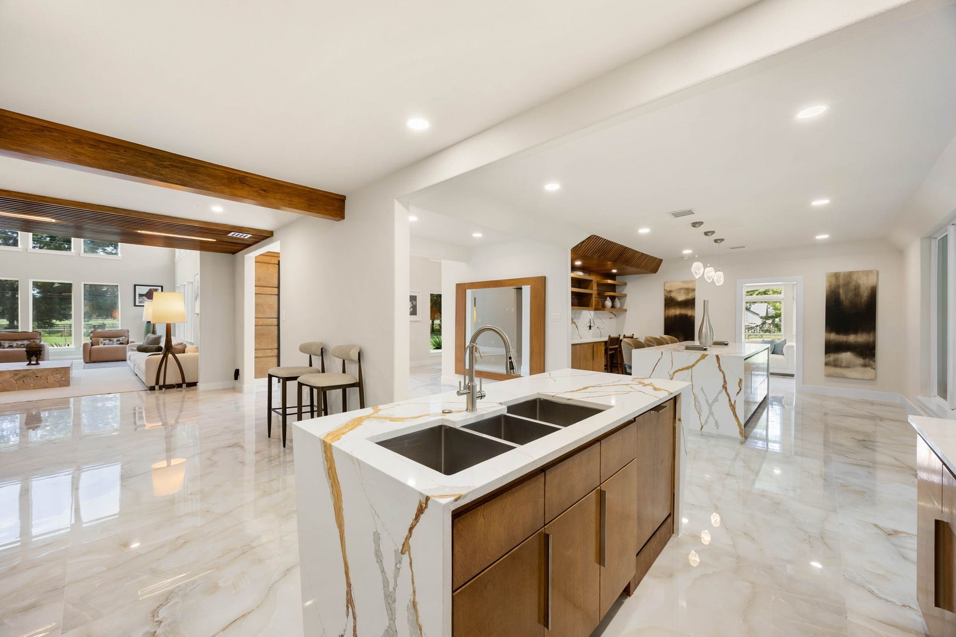 6830 Bois D Arc Lane, Fulshear, TX 77406 This gourmet kitchen is anchored by two oversized islands with waterfall marble countertops, rich wood cabinetry, and a sculptural wood range hood, all designed to make cooking and hosting feel effortless.