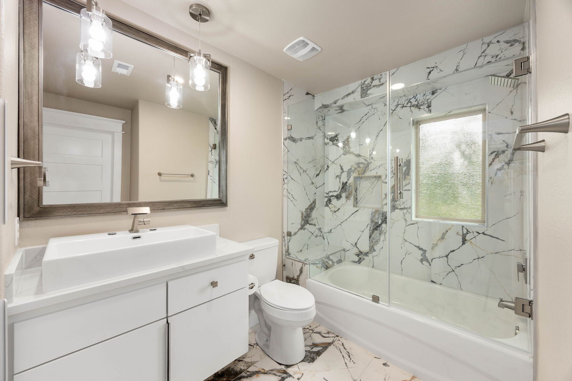 6830 Bois D Arc Lane, Fulshear, TX 77406 A secondary bath pairs a tub-shower combination with natural stone tile and a floating vanity.