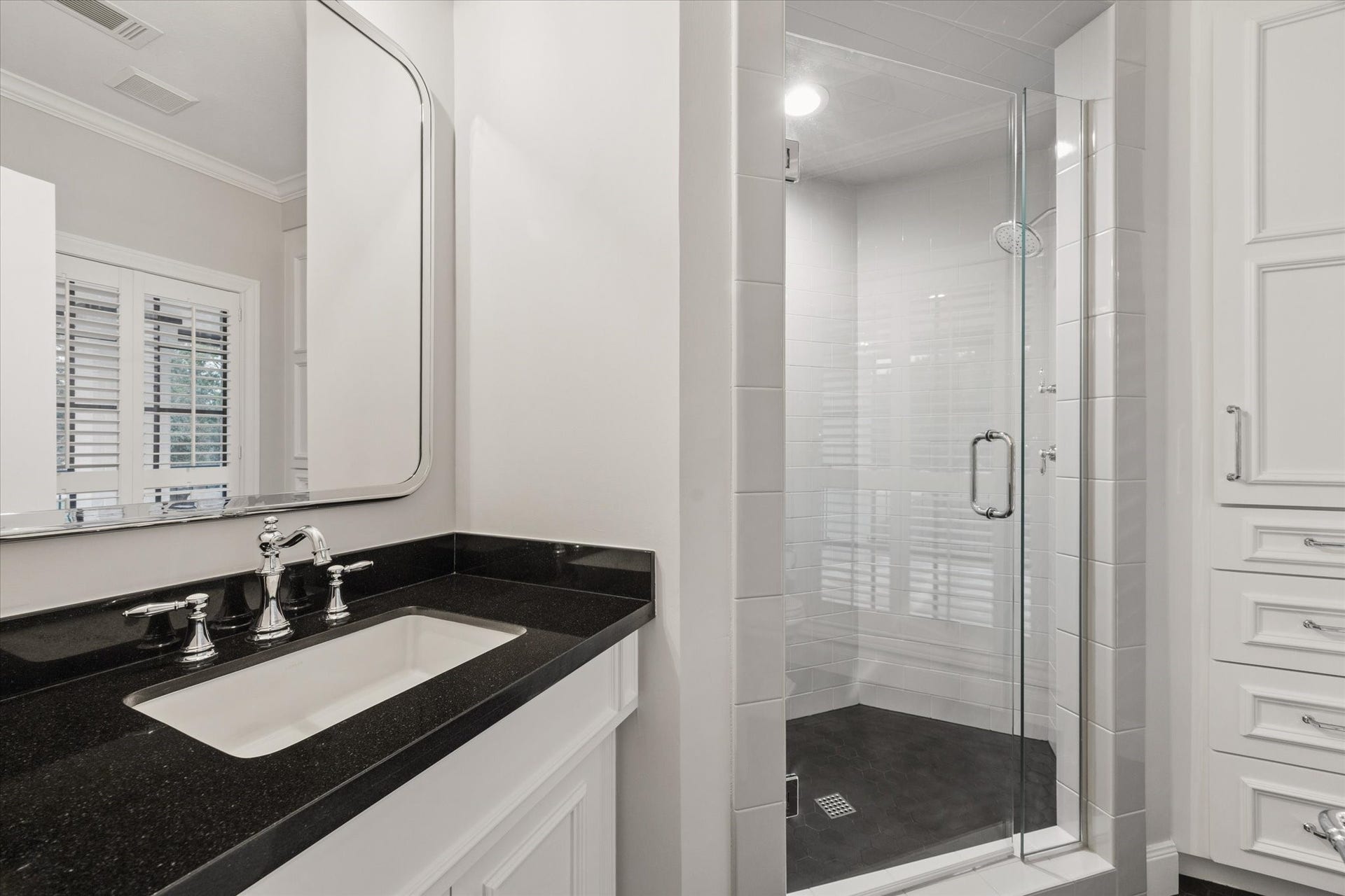 Elegant bathroom with a sleek black countertop, modern fixtures, and a spacious glass-enclosed shower for a luxurious experience.