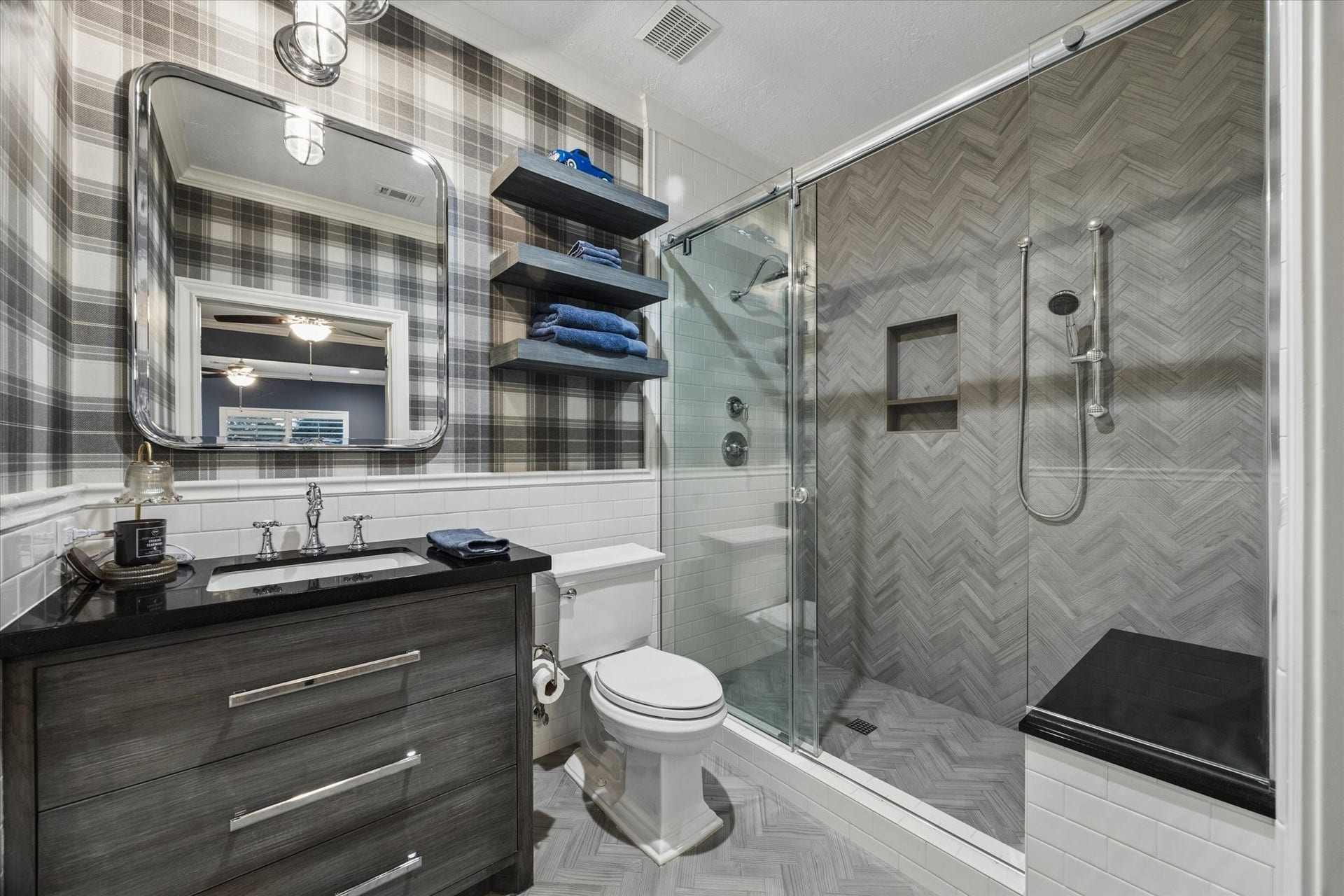 Ensuite bath featuring elegant wallpaper, a walk-in shower with a built-in bench, and custom tile work.