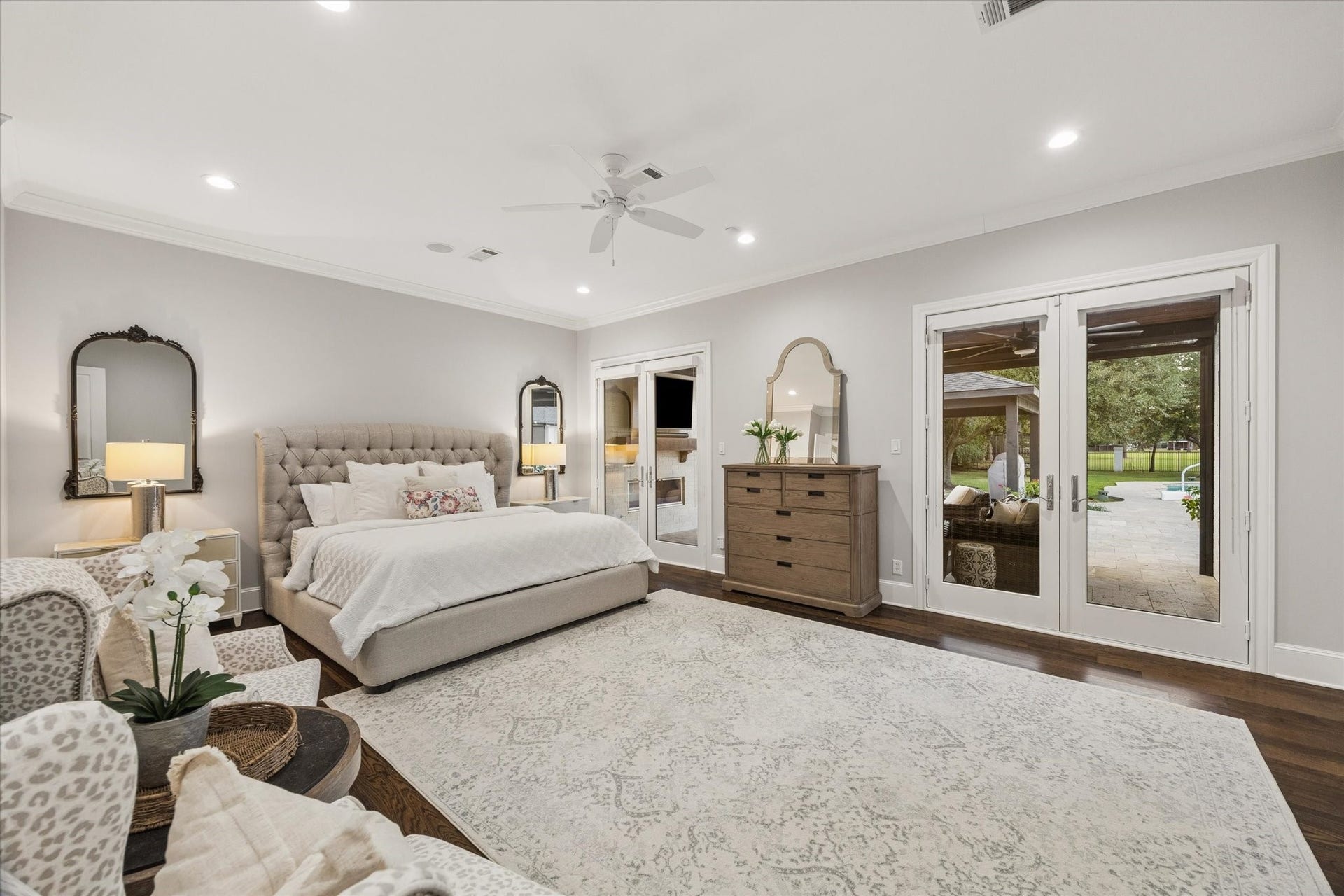 Spacious and elegant priamry bedroom with French doors opening to a serene outdoor patio.