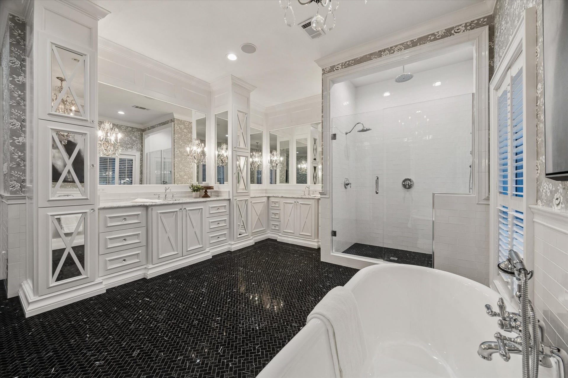Elegant primary bathroom on the first floor featuring mirror-beveled cabinetry, a separate shower, a soaking tub, and generous storage space.