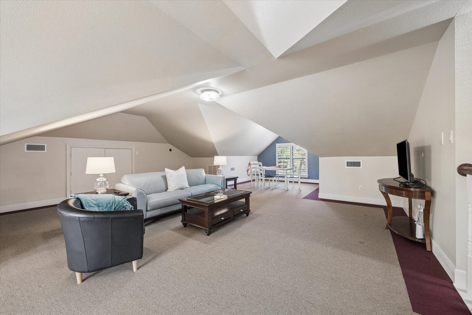 Spacious attic living area with cozy seating, ample natural light, and a versatile layout perfect for relaxation or entertaining.