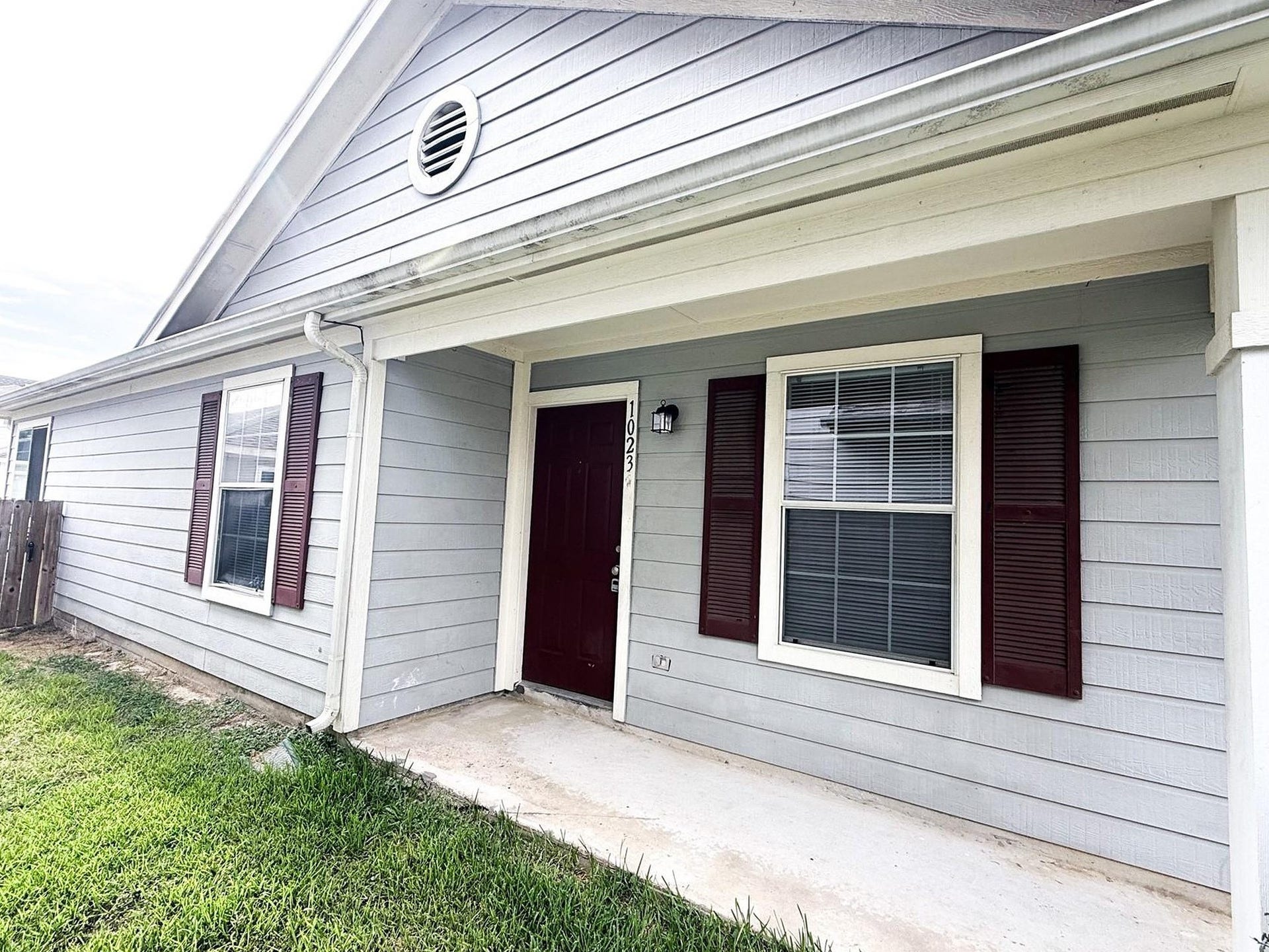 Inviting covered front porch with a rich red front door and matching shutters.  A warm spot to welcome guests or enjoy your morning coffee