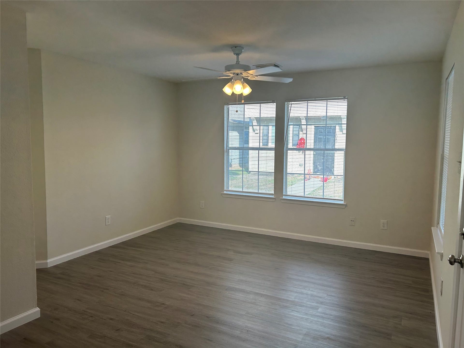 Spacious living area with dark wood flooring and lots of natural light.