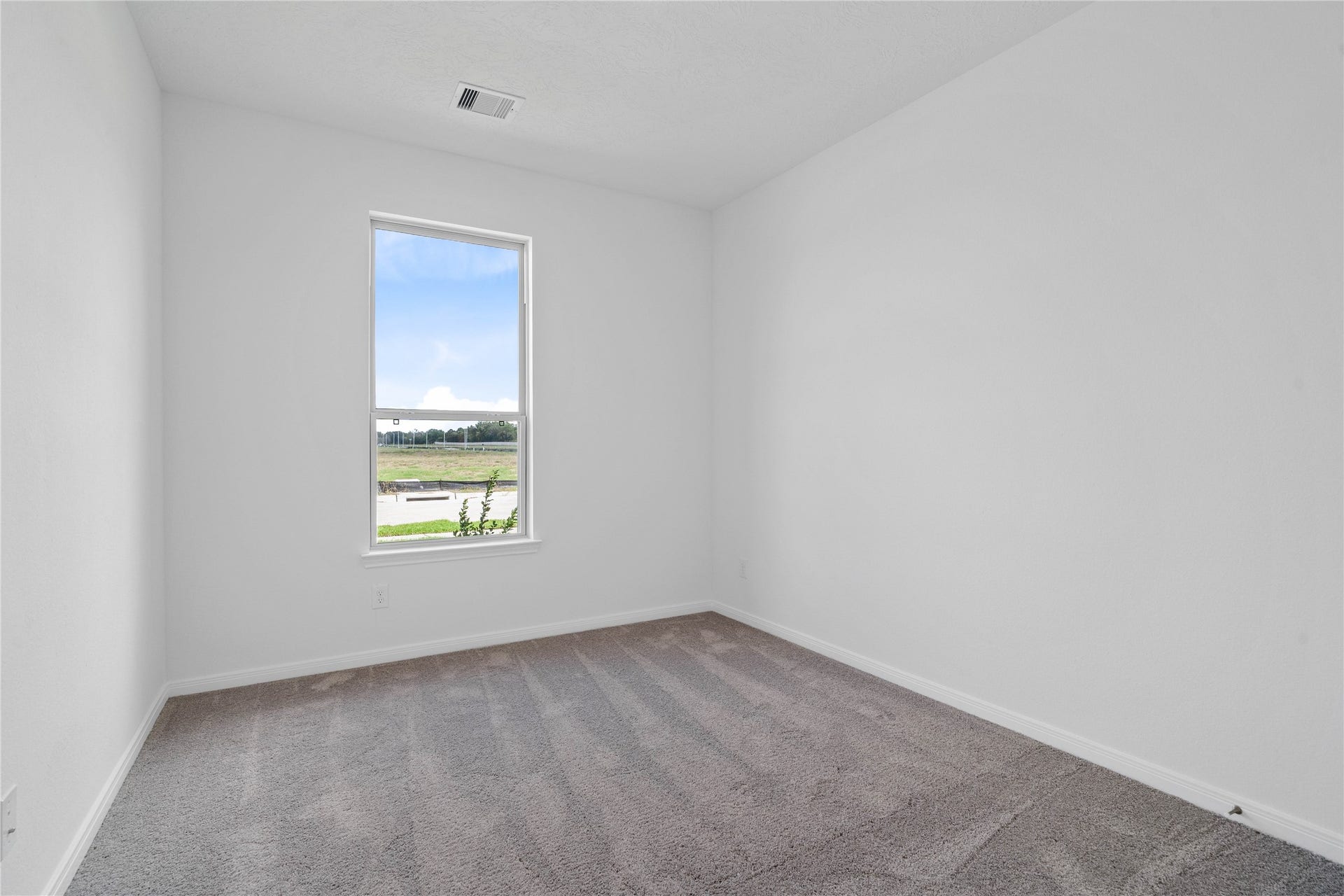 Located in the front of the home, this secondary bedroom offers comfort and style with plush carpeting, neutral paint tones, recessed lighting, a large window, and closet.