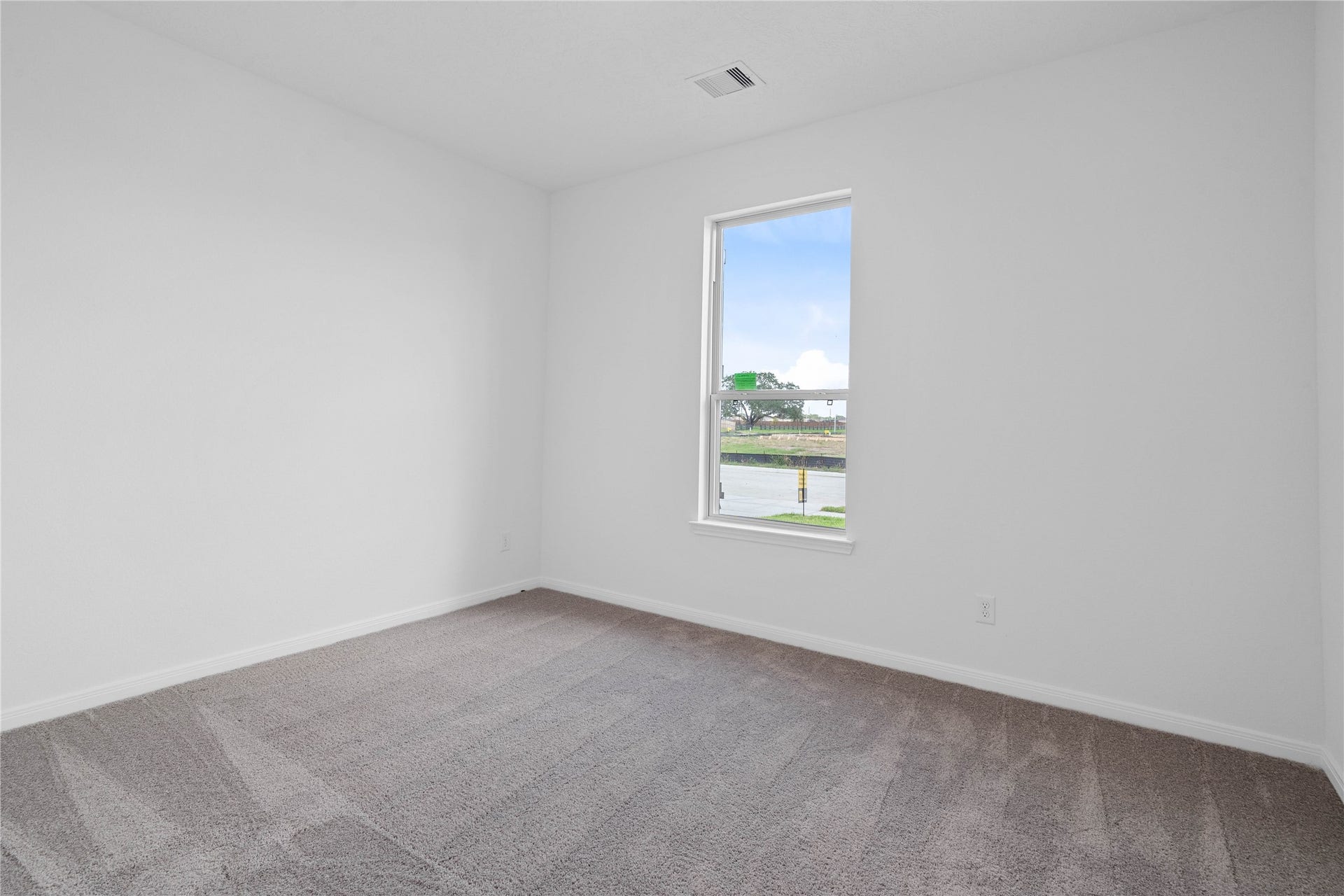 An additional secondary bedroom, also located at the front of the home features plush carpet, neutral paint, recessed lighting, windows, and closet space.