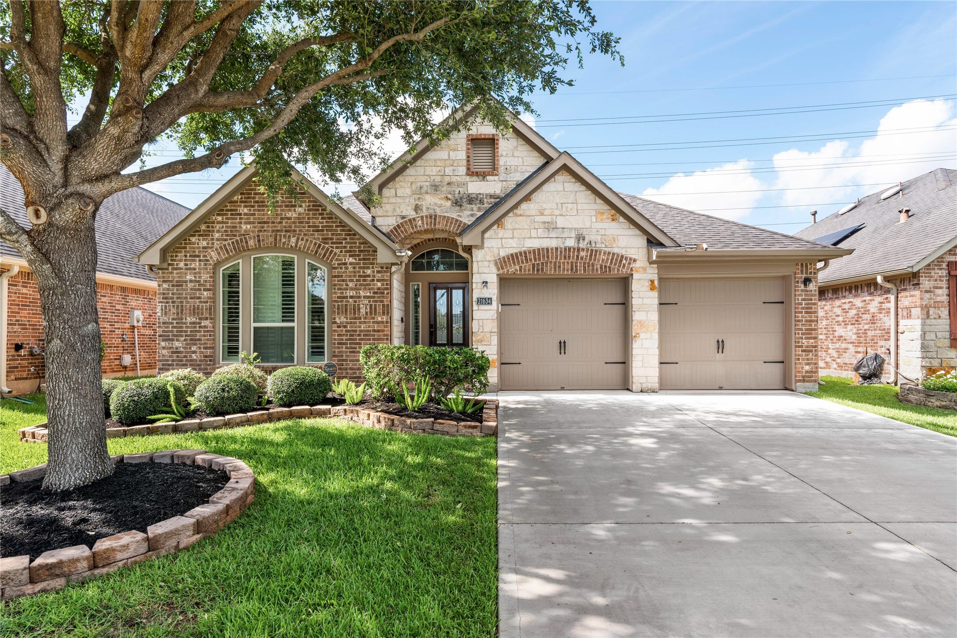 Exceptional exterior showcasing a sophisticated stone-brick accents, manicured landscaping and a welcoming entryway framed by mature trees.