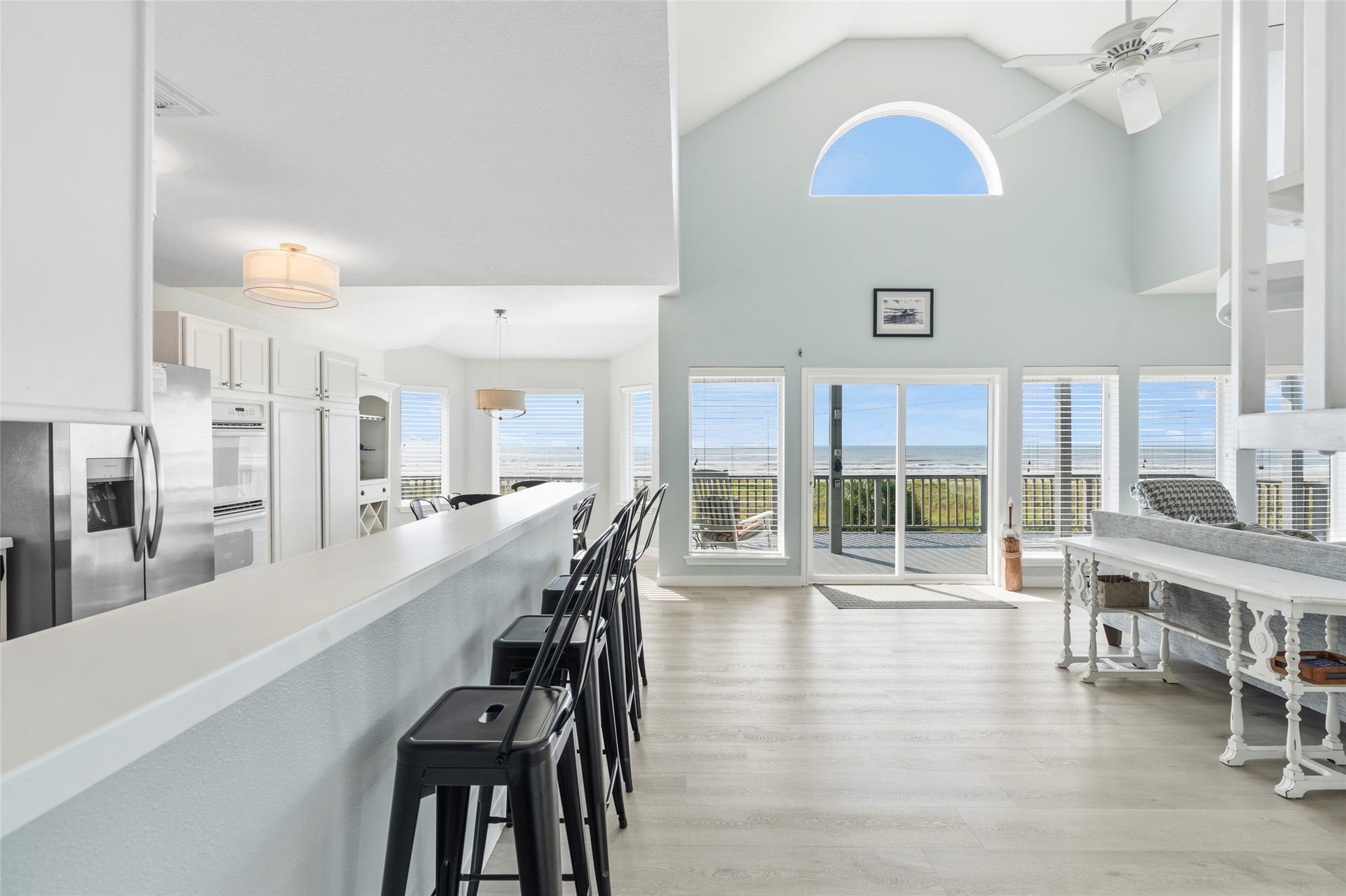 21631 Termini San Luis Pass Road, Galveston, TX 77554 Open-concept living space with a vaulted ceiling, expansive ocean views through large windows, and a modern kitchen featuring a long breakfast bar.