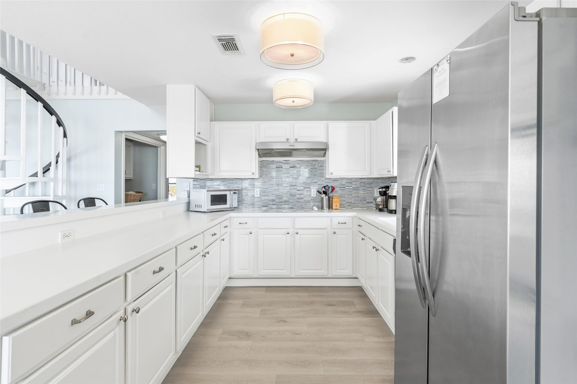 21631 Termini San Luis Pass Road, Galveston, TX 77554 Bright and modern kitchen featuring sleek white cabinetry, stainless steel appliances, and a stylish tile backsplash, complemented by ample counter space and contemporary lighting.
