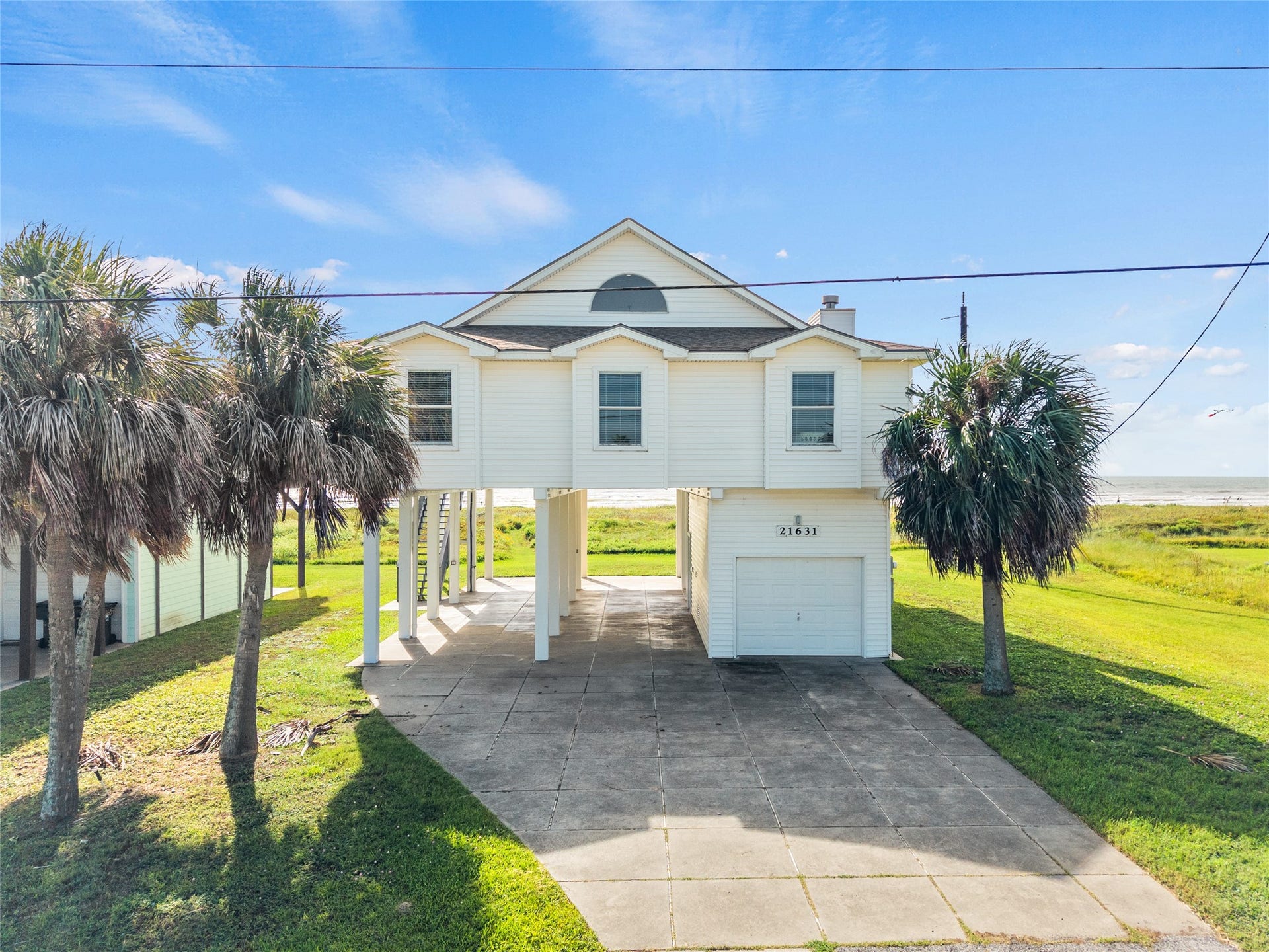 21631 Termini San Luis Pass Road, Galveston, TX 77554 Coastal home with ocean views features a spacious driveway and lush palm trees.