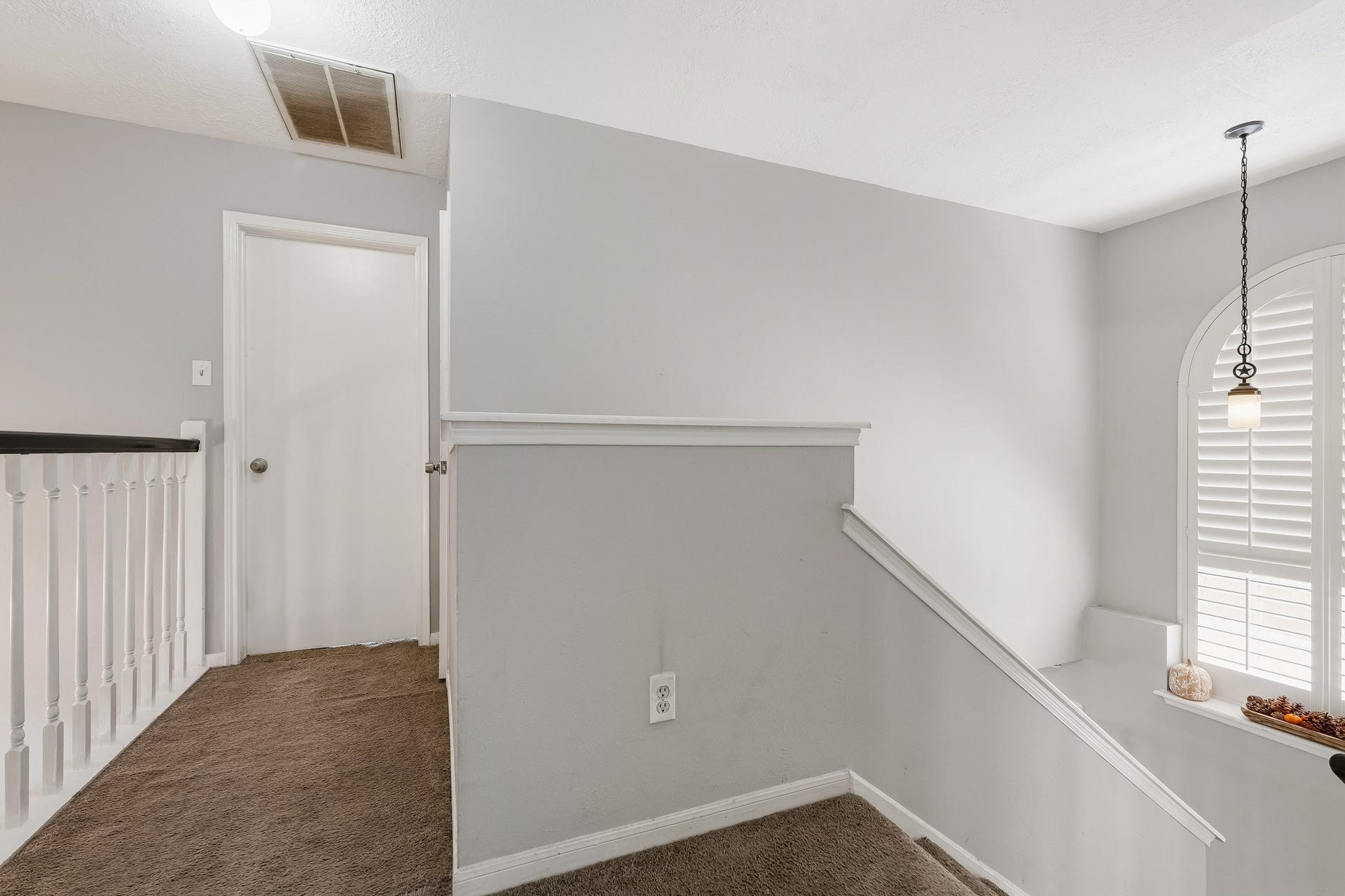 4811 Red Lantern Drive, Friendswood, TX 77546 Bright and inviting upstairs landing with soft carpeting, a charming pendant light, and a window with shutters, offering a cozy transition to the upper rooms.