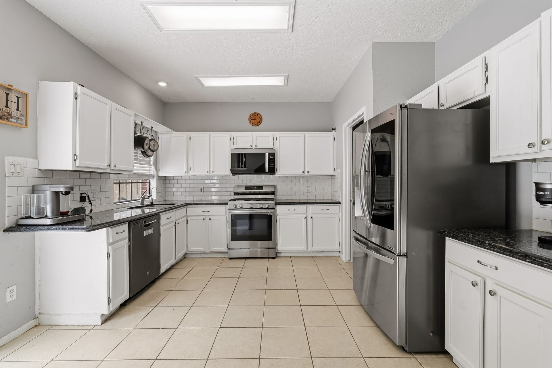 4811 Red Lantern Drive, Friendswood, TX 77546 Spacious kitchen with sleek stainless steel appliances, white cabinets, and a stylish subway tile backsplash, offering ample counter space and modern lighting.
