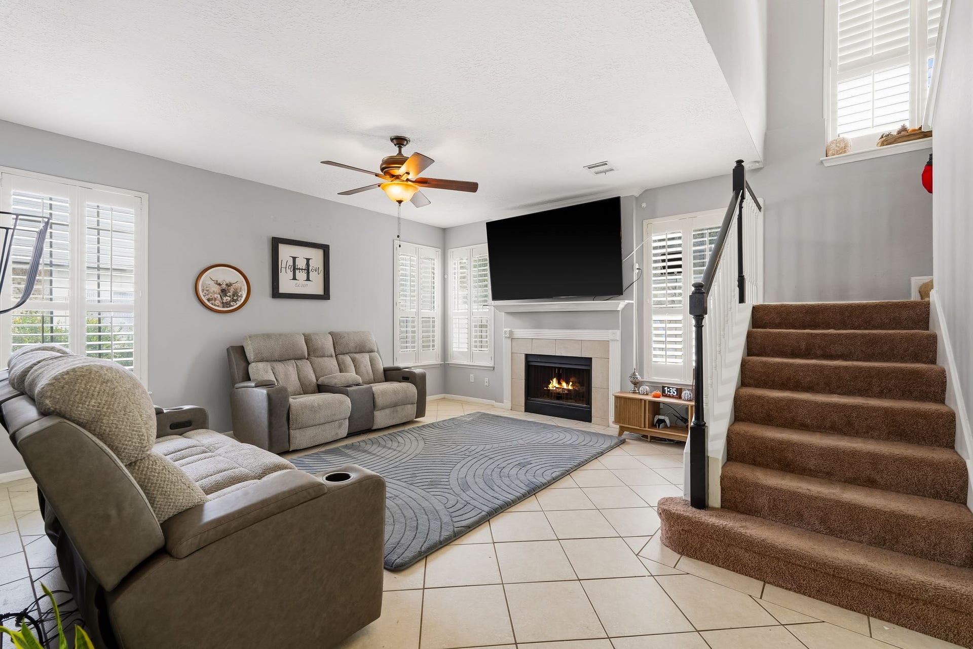 4811 Red Lantern Drive, Friendswood, TX 77546 Cozy living room with a modern fireplace, natural light from shuttered windows, and a warm, neutral color scheme.