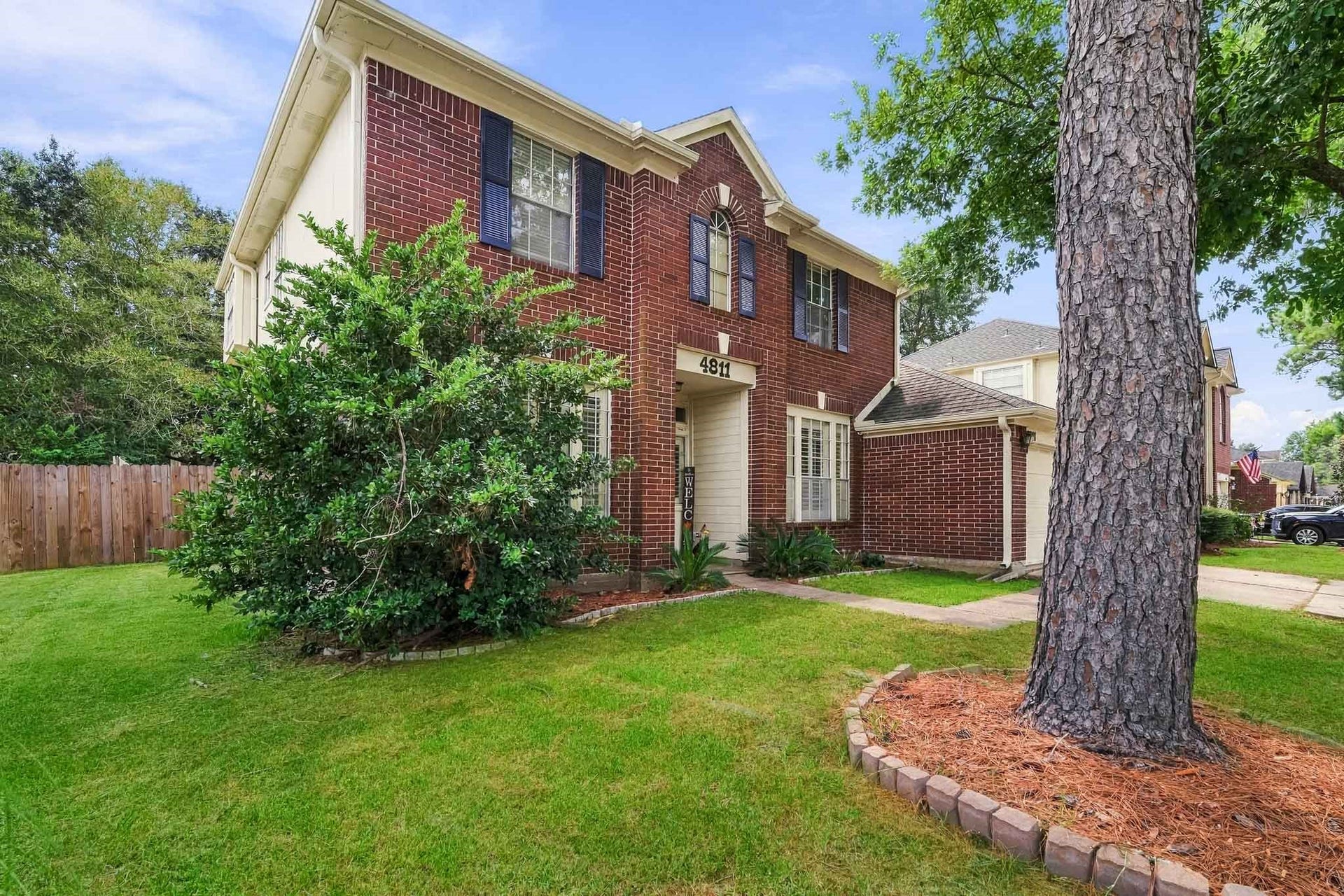 4811 Red Lantern Drive, Friendswood, TX 77546 Charming brick two-story home with lush landscaping and a welcoming front entrance, set on a spacious lot.