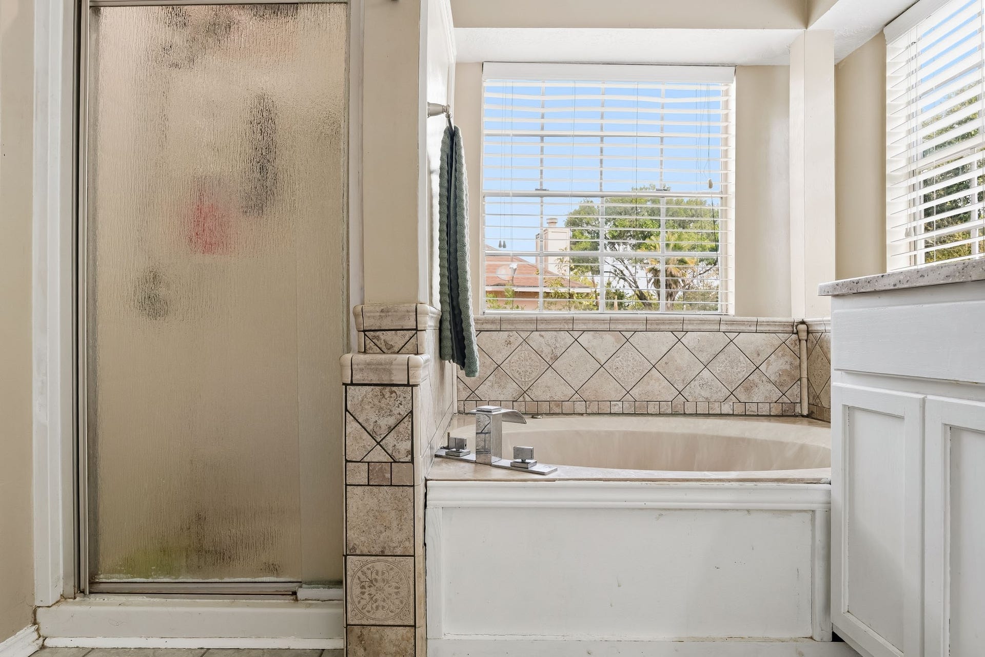4811 Red Lantern Drive, Friendswood, TX 77546 Elegant bathroom featuring a spacious soaking tub with stylish tile surround and a separate glass-enclosed shower, offering a serene retreat with abundant natural light.