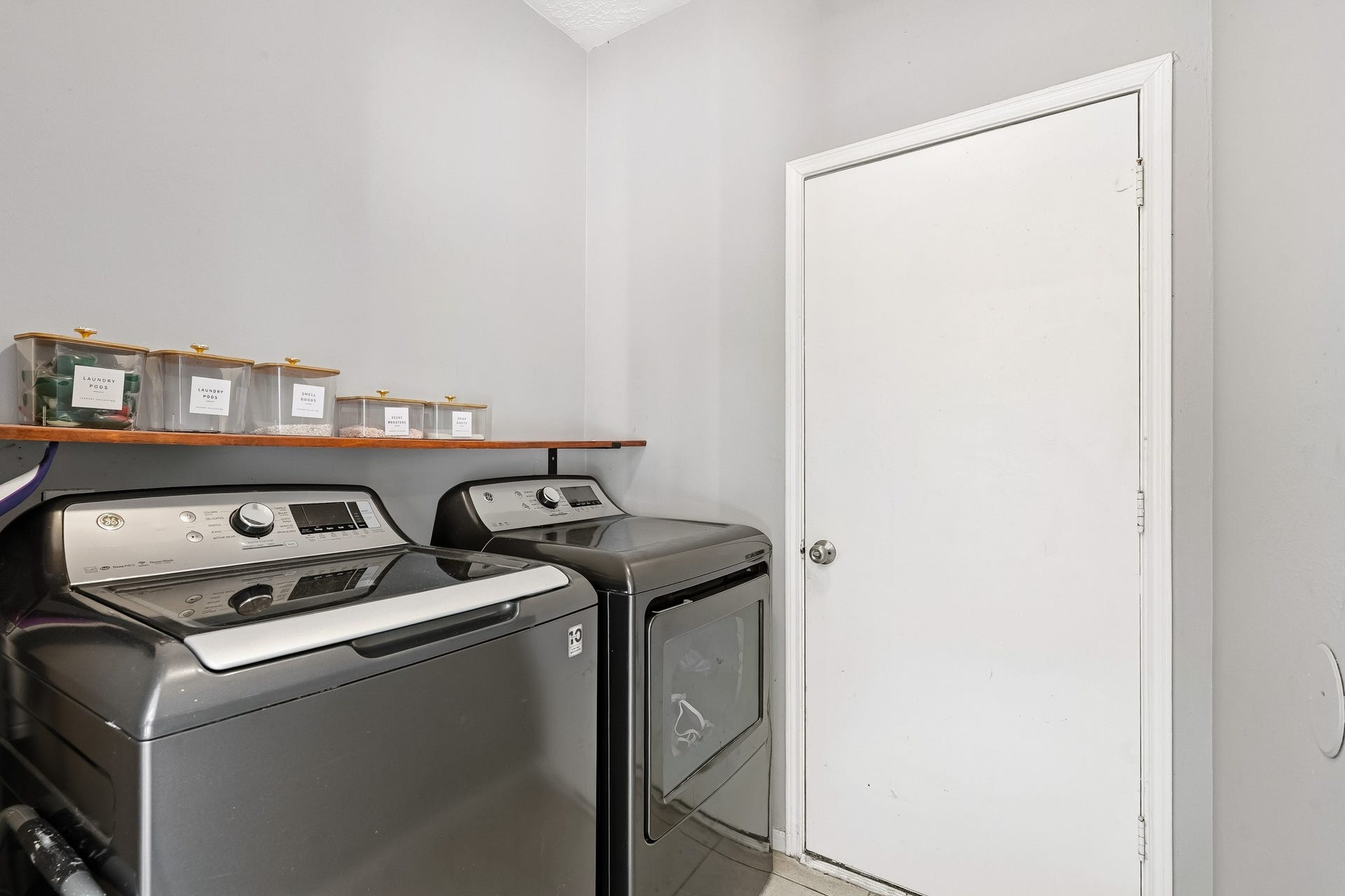 4811 Red Lantern Drive, Friendswood, TX 77546 Modern laundry room with sleek washer and dryer, complemented by a convenient shelf for storage.