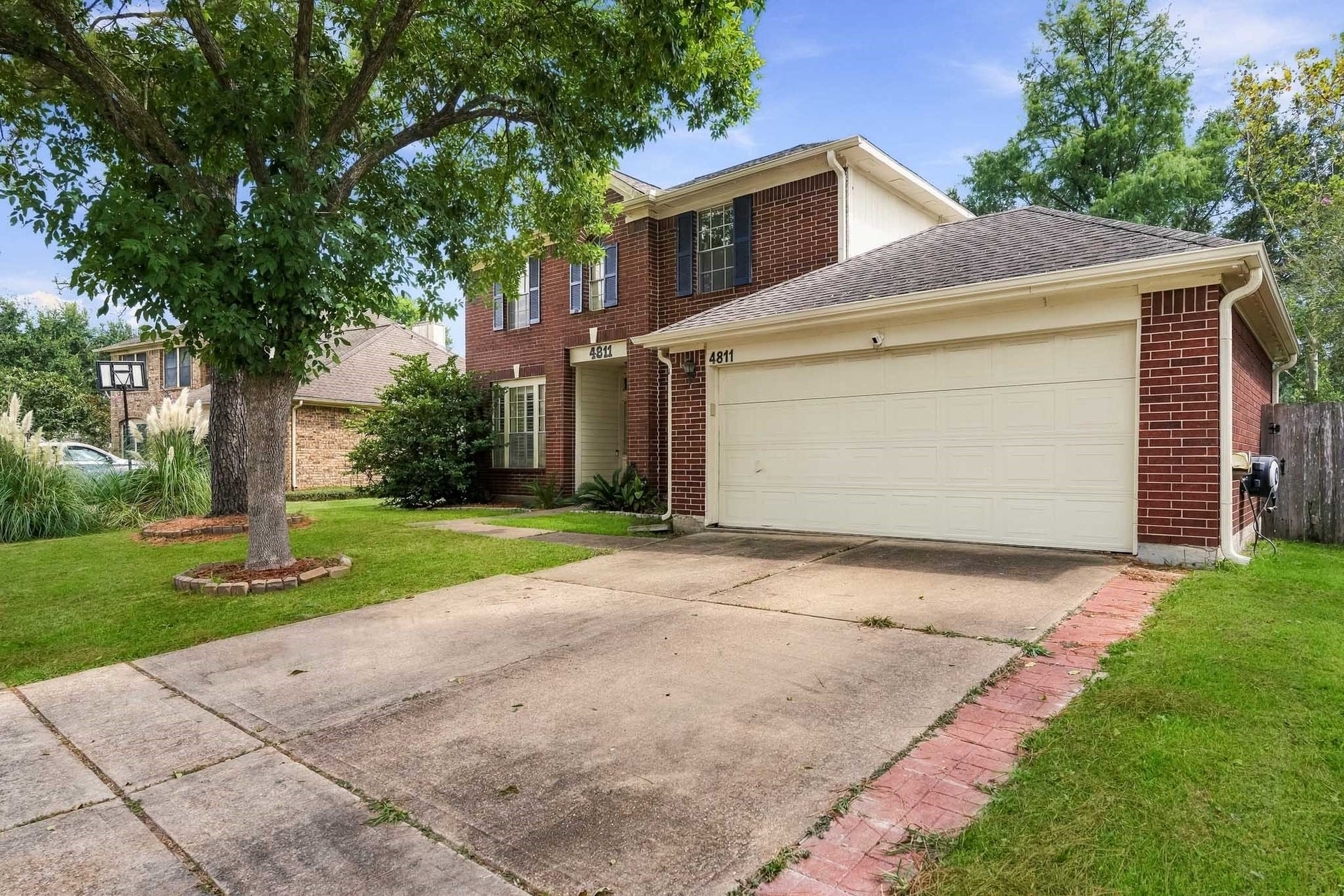 4811 Red Lantern Drive, Friendswood, TX 77546 Charming two-story brick home with a spacious two-car garage, lush front yard, and mature trees, offering great curb appeal in a serene neighborhood.