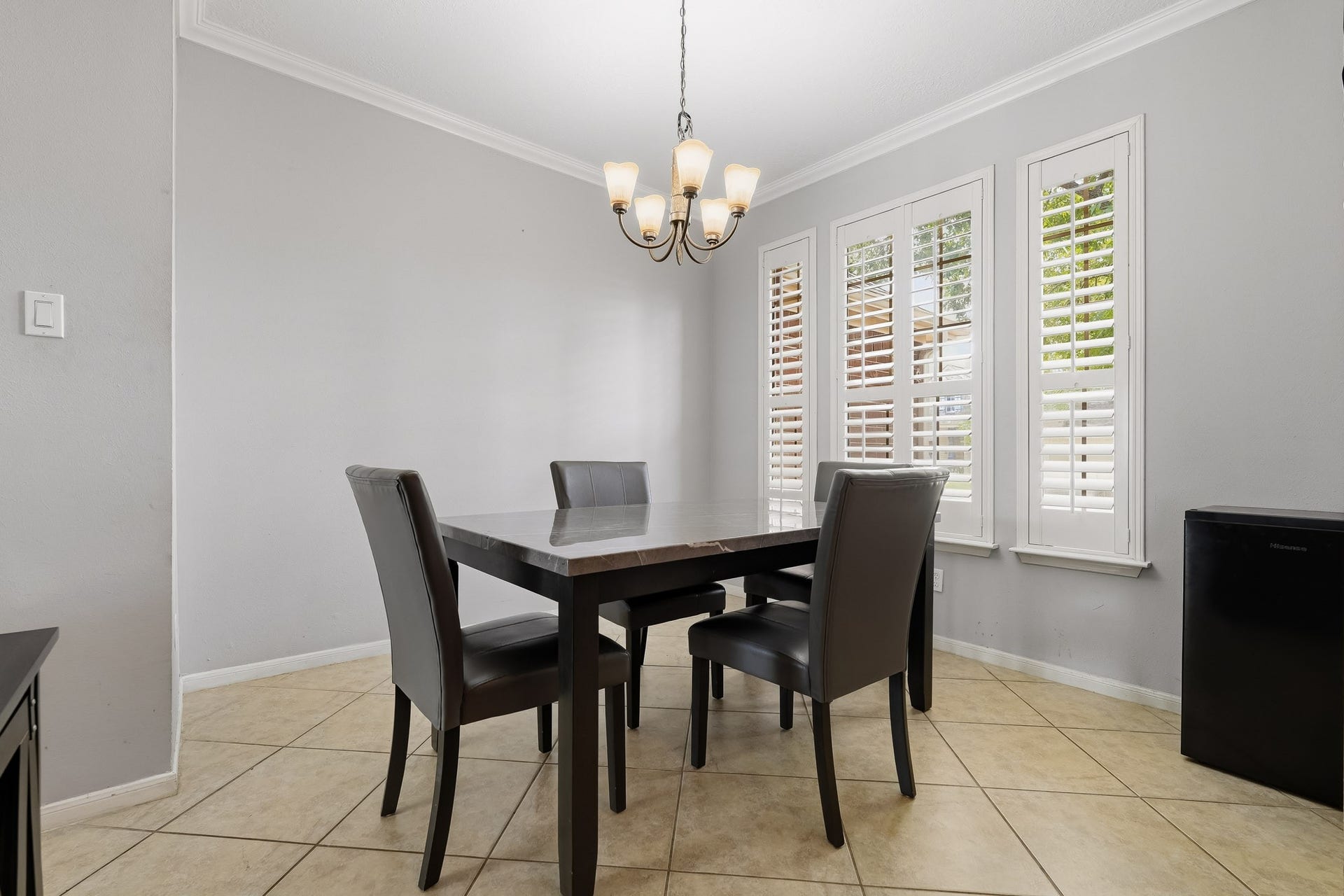 4811 Red Lantern Drive, Friendswood, TX 77546 Bright dining area with elegant tile flooring, a modern chandelier, and large windows featuring plantation shutters.