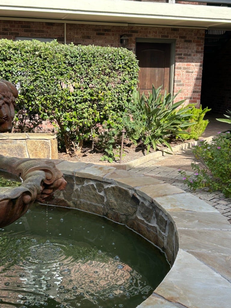 402 Post Office Street, #109, Galveston, TX 77550 Prettiest condo courtyard in Galveston. There is a large three-tier fountain on one end of the courtyard and a pool at the other end. The front door for Unit 109 is in the background.