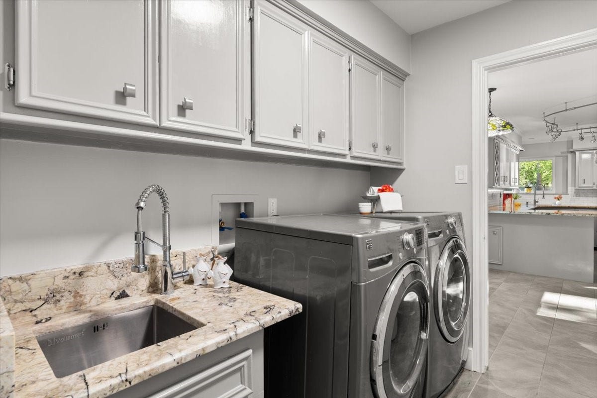 This spacious laundry room boasts built-in
cabinets, a sink, a closet, and space for a large
refrigerator.