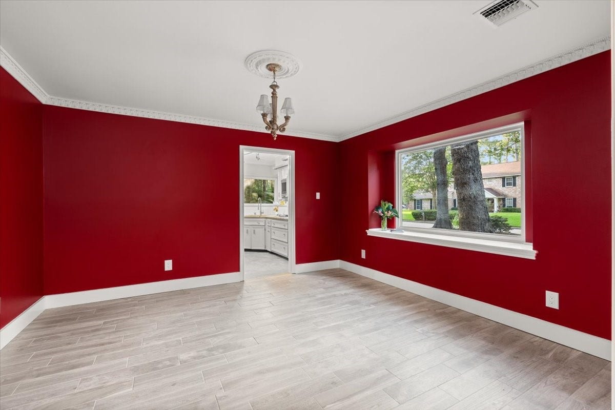 Bright and inviting dining room with elegant red
walls, large window views, and seamless flow to
the kitchen.