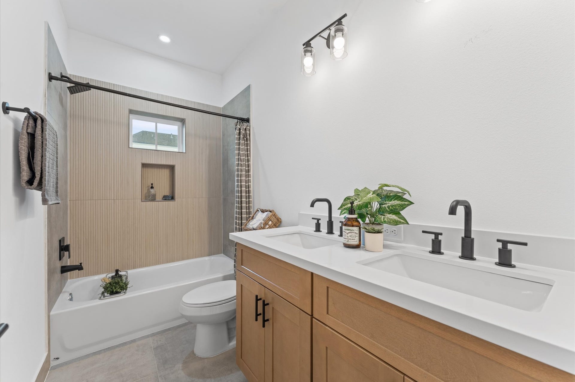 Beautifully appointed Jack and Jill bathroom nestled between two secondary bedrooms on the first floor, designed to balance style and functionality. Each bedroom enjoys private access to the shared space, which features a sleek tub-shower combo, perfect for both quick rinses and relaxing soaks. Contemporary tilework, dual vanities, and bright lighting add modern appeal, while thoughtful layout enhances privacy and ease of use.
