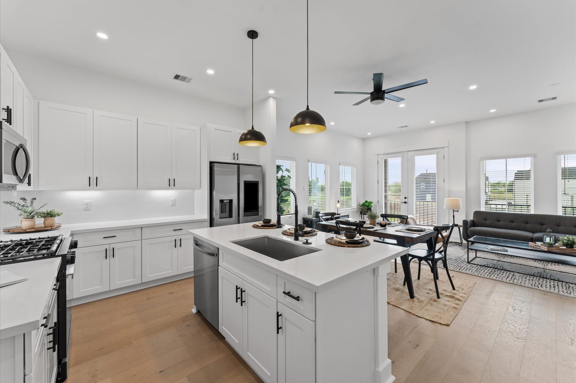 This centrally positioned kitchen island serves as a stylish anchor within the open-concept layout, offering clear sightlines to the dining area and the living space. Its placement encourages seamless interaction, whether prepping meals or entertaining guests, while natural light pours in through the nearby windows. The islands sleek design and functional surface make it a hub of activity tying together comfort and sophistication.