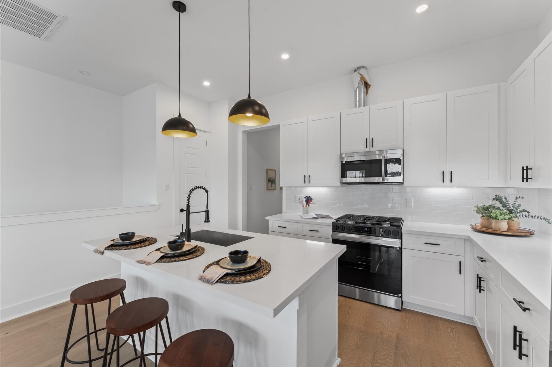 This centrally positioned kitchen island serves as a stylish anchor within the open-concept layout, offering clear sightlines to the dining area and the living space. Its placement encourages seamless interaction, whether prepping meals or entertaining guests, while natural light pours in through the nearby windows. The islands sleek design and functional surface make it a hub of activity tying together comfort and sophistication.
