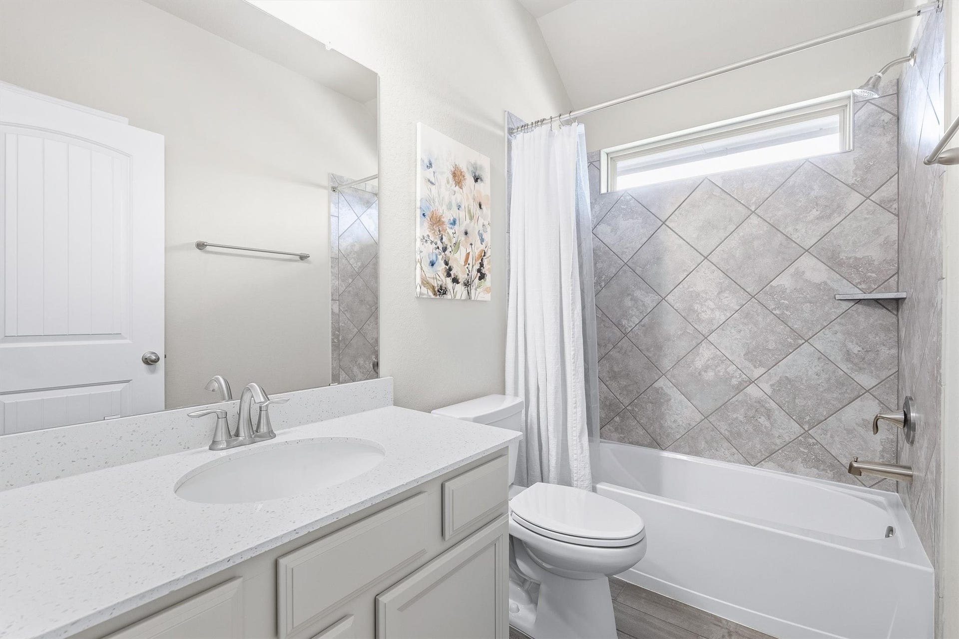9034 Japonica Drive, Rosenberg, TX 77469 Bright and modern upstairs bathroom featuring a sleek vanity with a quartz countertop, elegant tile surround in the shower, and a large mirror enhancing the spacious feel.