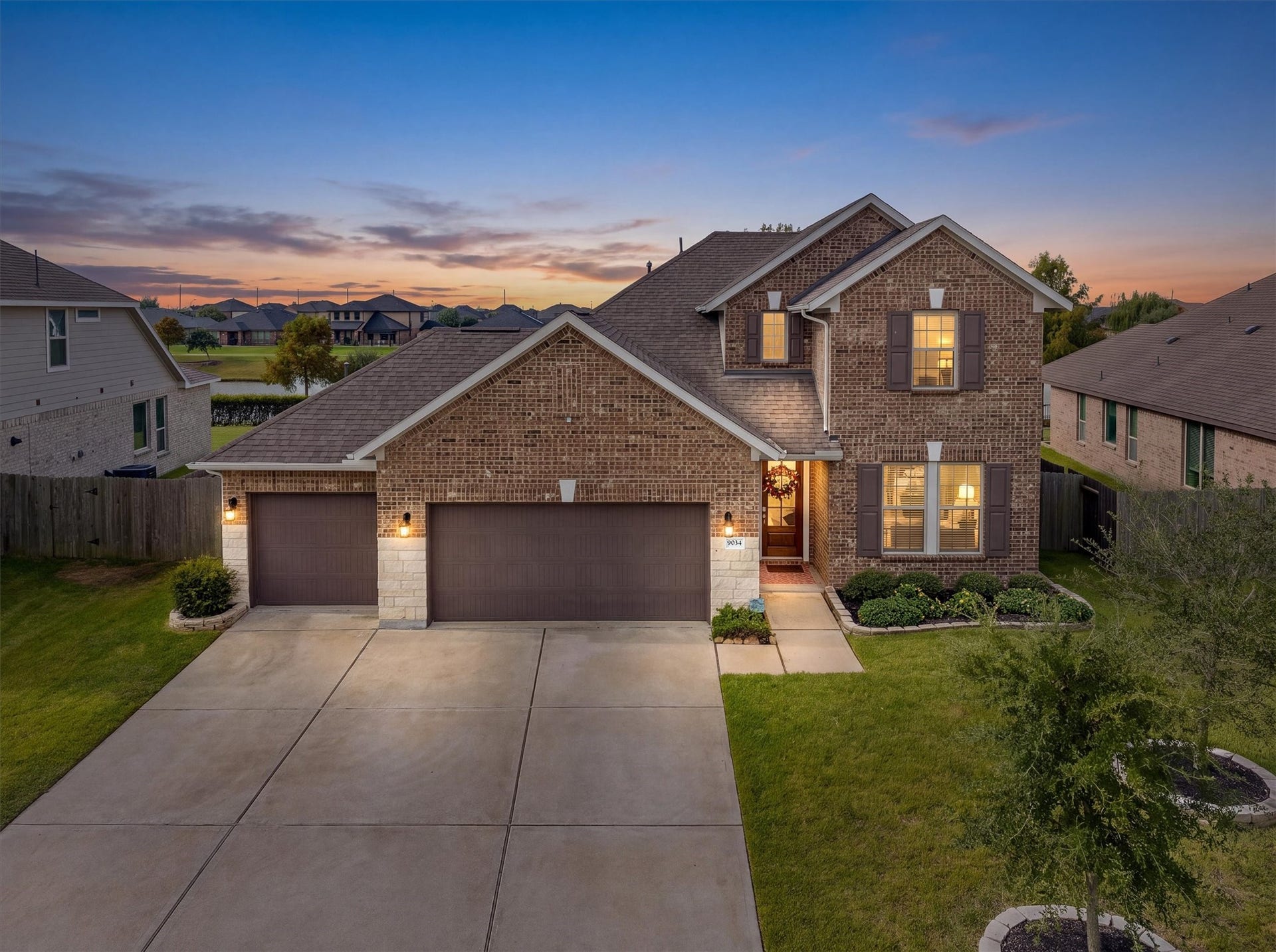 9034 Japonica Drive, Rosenberg, TX 77469 A striking brick and stone facade glowing under a magnificent sunset sky.