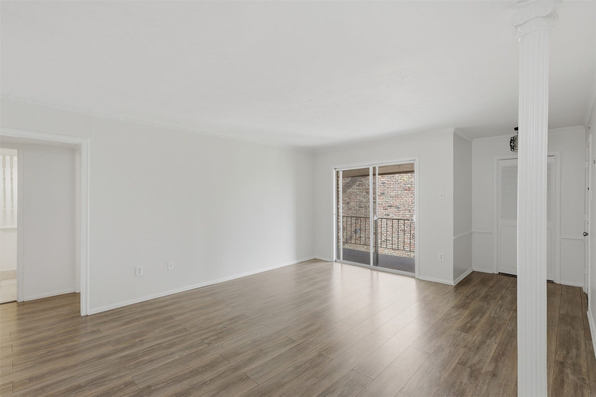 7600 Burgoyne Road, #250, Houston, TX 77063 Experience the perfect blend of comfort and style in this spacious living area, featuring elegant hardwood floors and abundant natural light from sliding glass doors leading to a charming balcony.