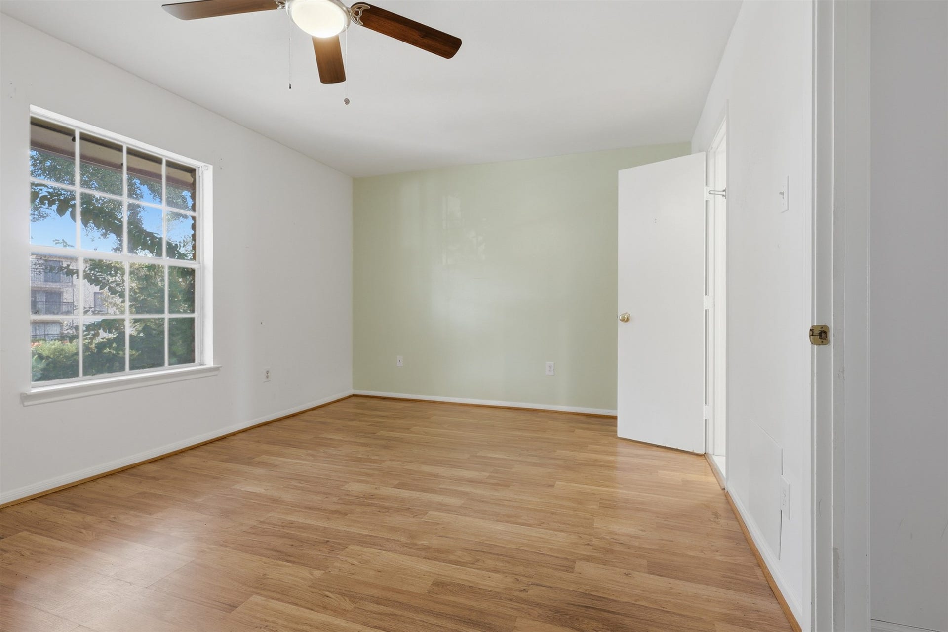 7600 Burgoyne Road, #250, Houston, TX 77063 Spacious and serene, the primary bedroom boasts abundant natural light, warm wood flooring, and a calming neutral palette, perfect for relaxation.