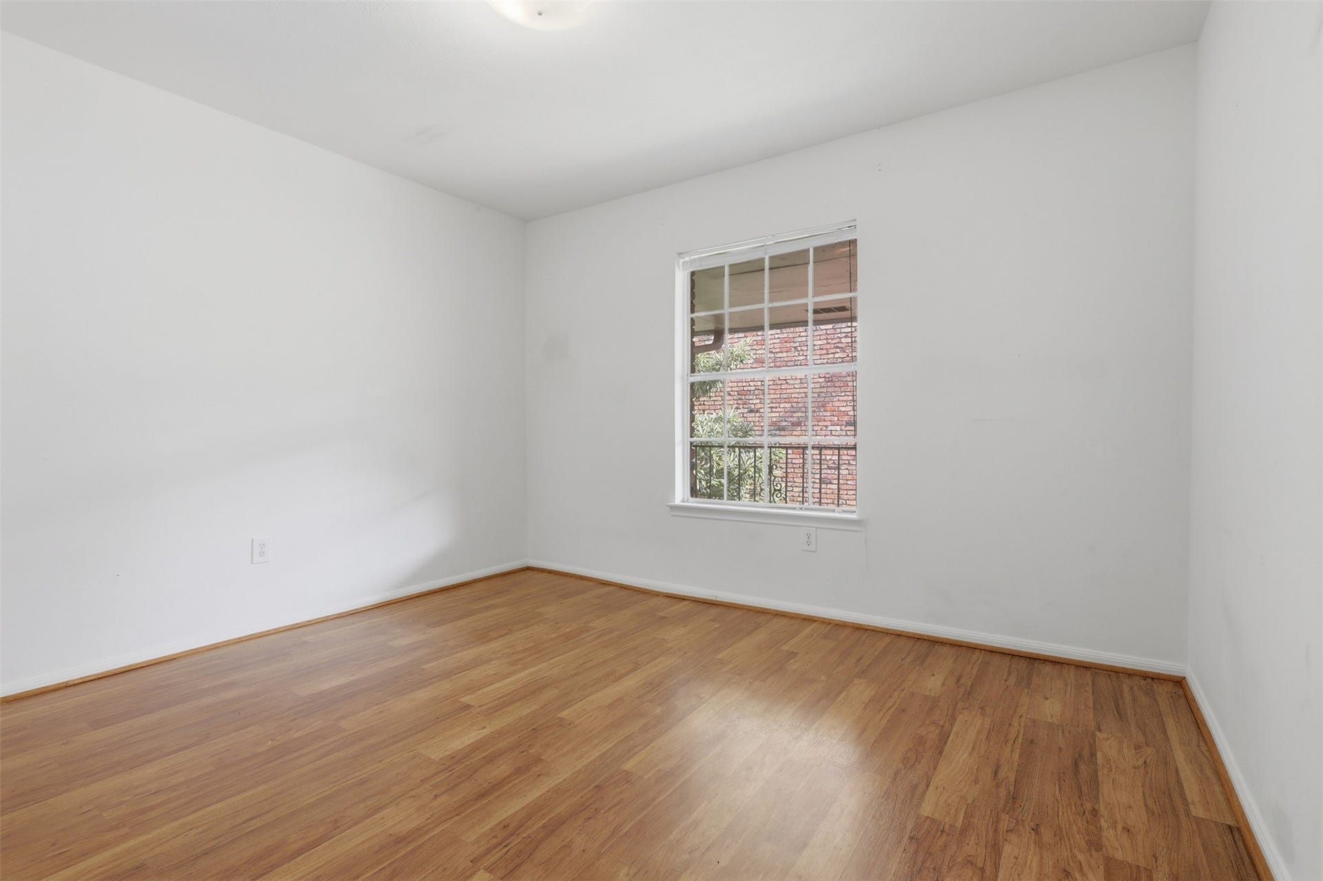 7600 Burgoyne Road, #250, Houston, TX 77063 Bright and inviting, this second bedroom offers a serene space with natural light streaming through a large window, perfectly complementing the warmth of its hardwood floors.