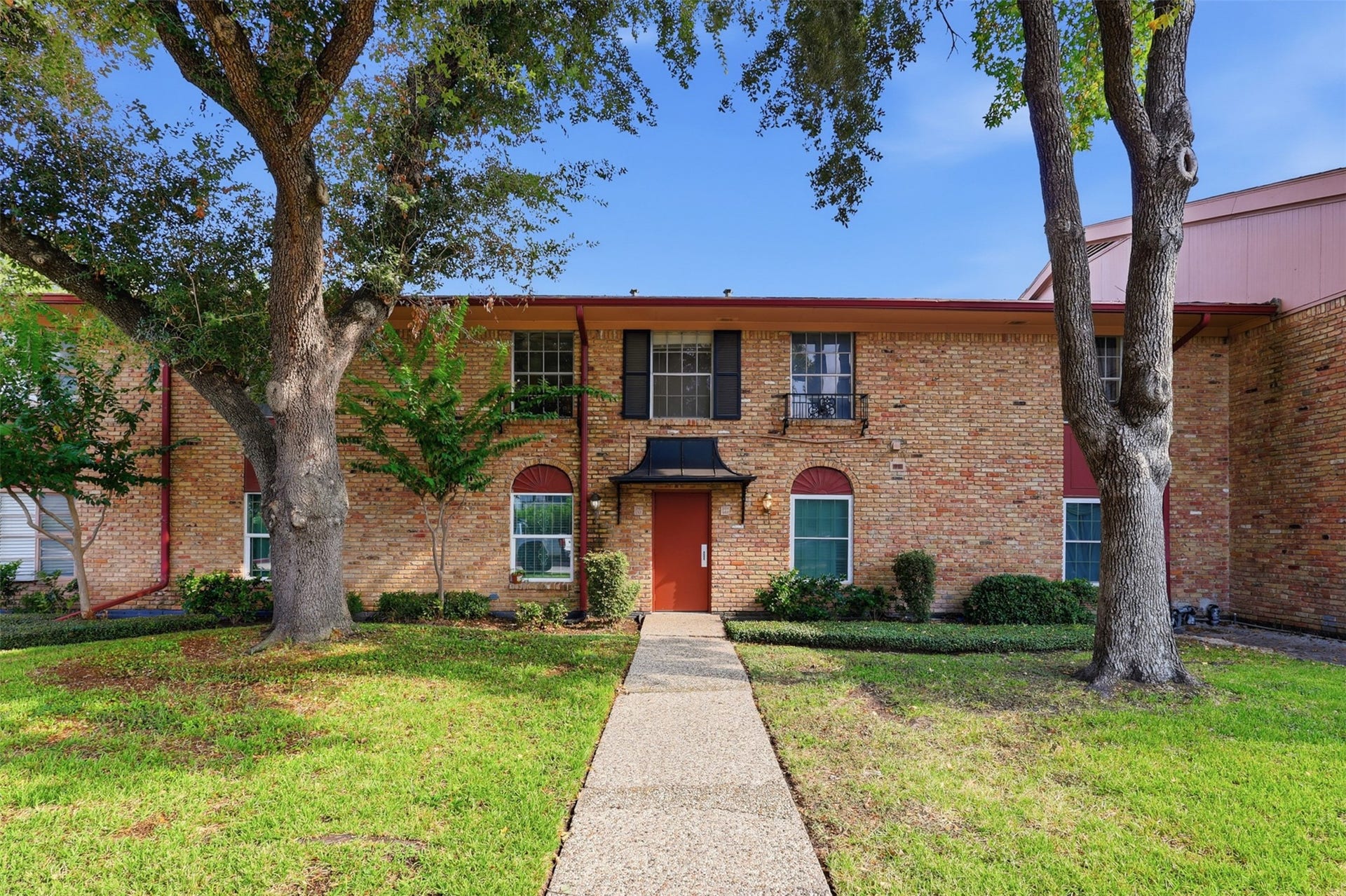 7600 Burgoyne Road, #250, Houston, TX 77063 Charming brick facade welcomes you to this inviting entrance, framed by mature trees and lush greenery, offering a perfect blend of elegance and warmth.