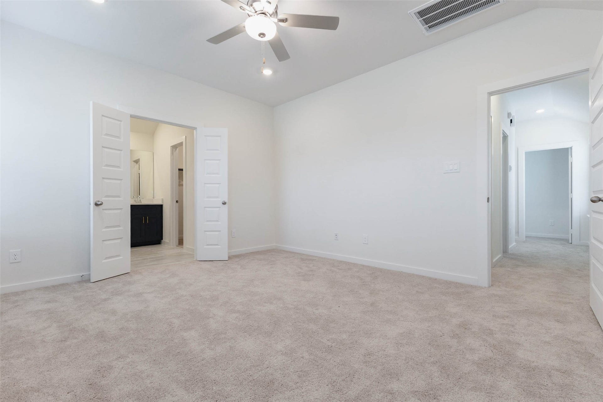 1115 Santee Court, Rosharon, TX 77583 The primary bedroom from another angle shows how well it is sized, with a ceiling fan and two large doors that open to the bath and a hallway. Soft carpet underfoot and neutral walls create a calm, restful setting, and there is enough room for a desk or reading chair beside the window. It is a peaceful place to end the day.