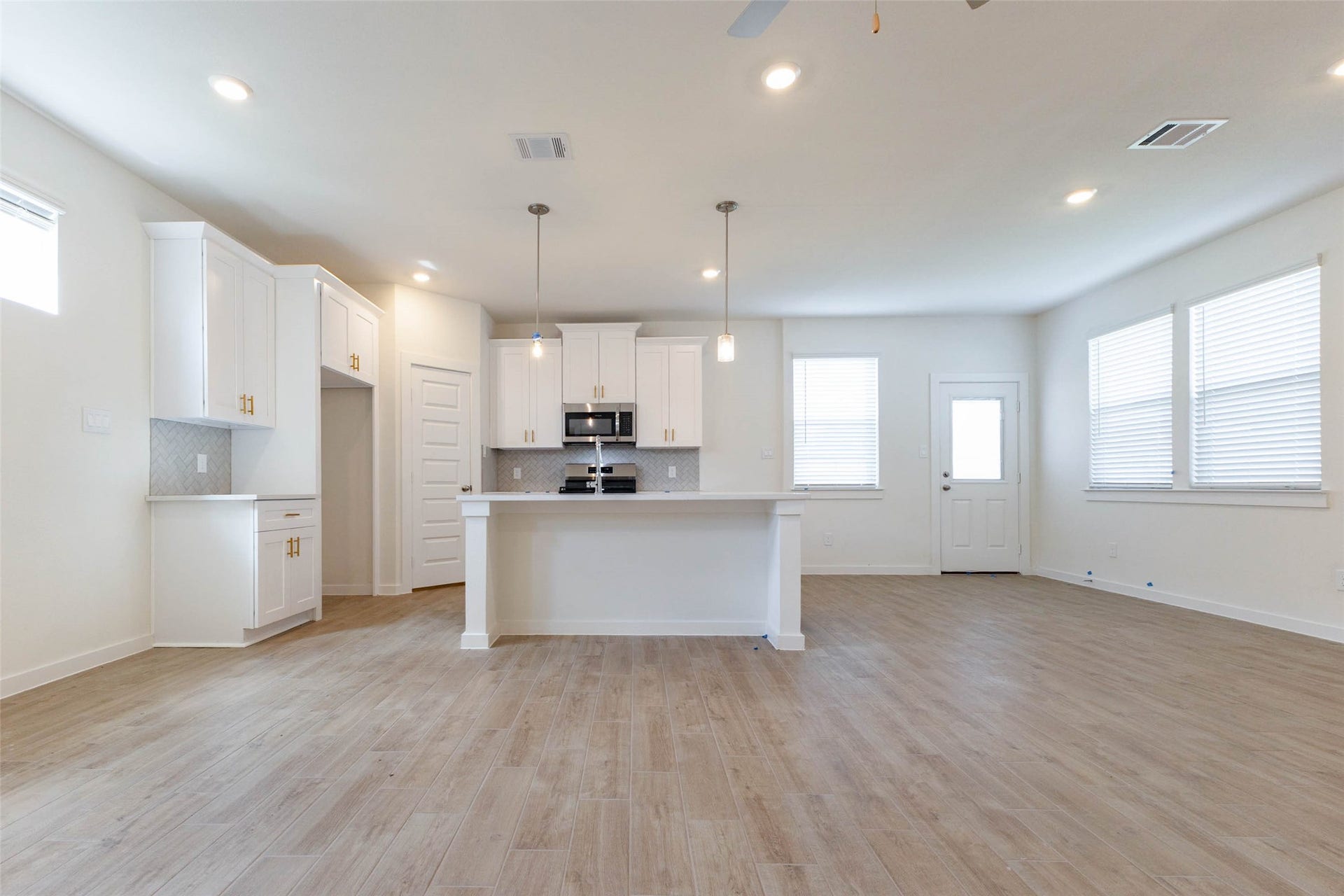 1115 Santee Court, Rosharon, TX 77583 The kitchen opens straight into the main living area, so the cook can chat with guests from behind the island. White shaker cabinets, a tiled backsplash and two pendant lights set a bright, modern tone, and a back door and large windows let natural light pour across the wood-look floors. It is an easy layout for hosting game day, holidays or weeknight dinners.